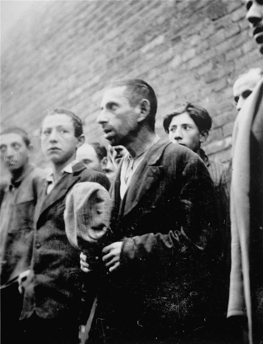 Jewish men and youth are lined-up against a wall during an action in Plonsk.