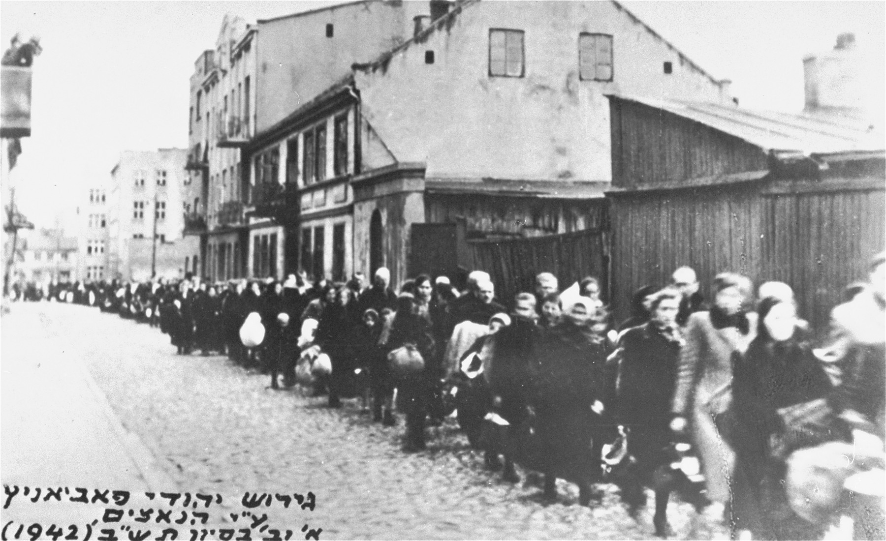 A long column of Jews marches through the streets of Pabianice during a deportation action.
