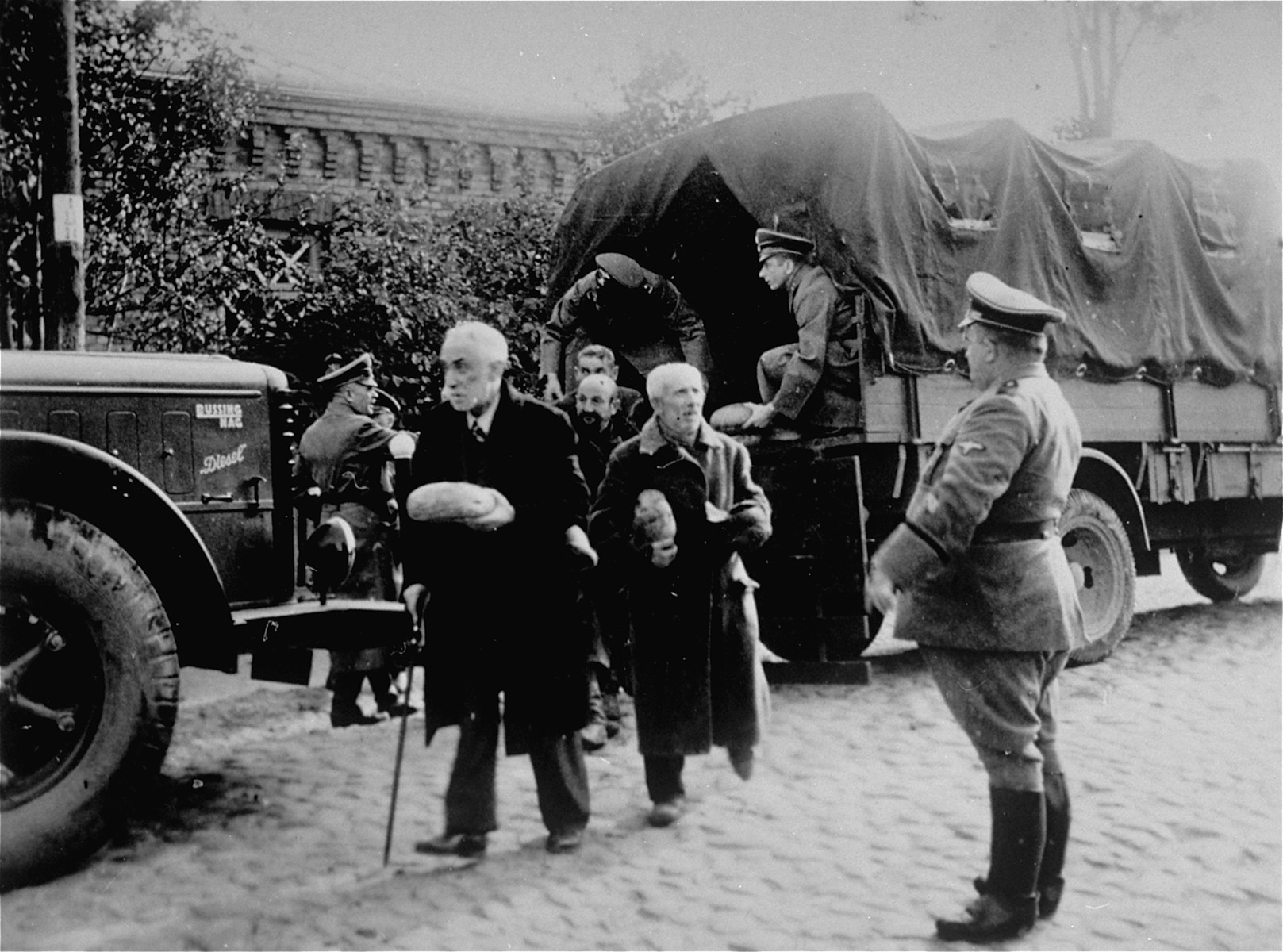 Jewish men from Plonsk receive loaves of bread that Germans distribute from the back of a truck.