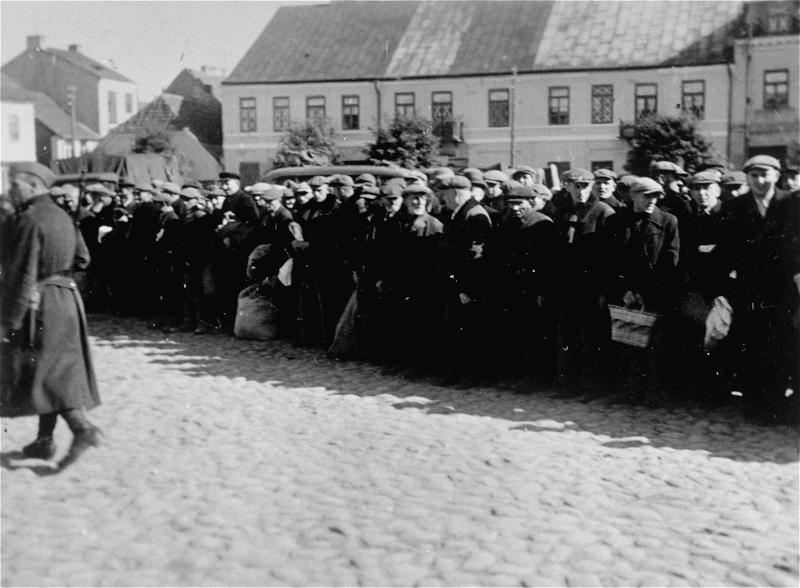 Jewish men are lined up along the perimeter of the town square in Raciaz.