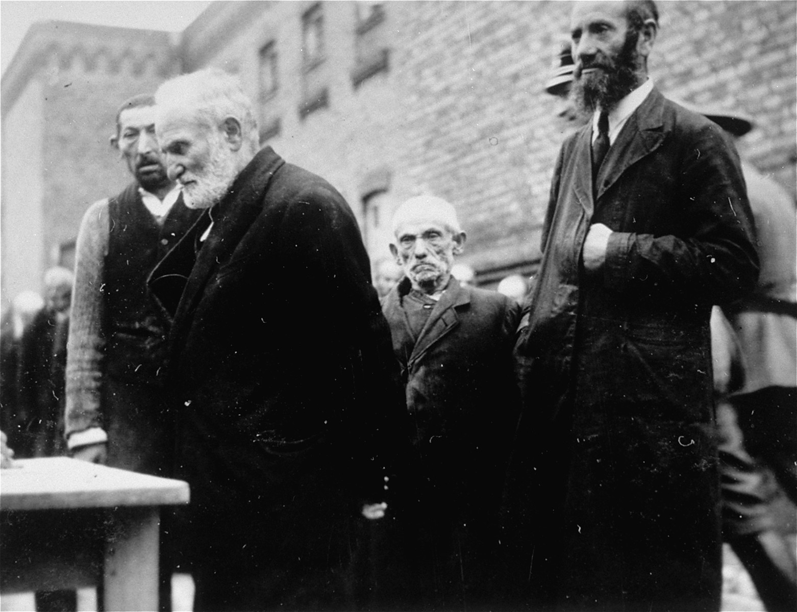 Elderly Jewish men who have been rounded-up in Plonsk wait in line to be registered.