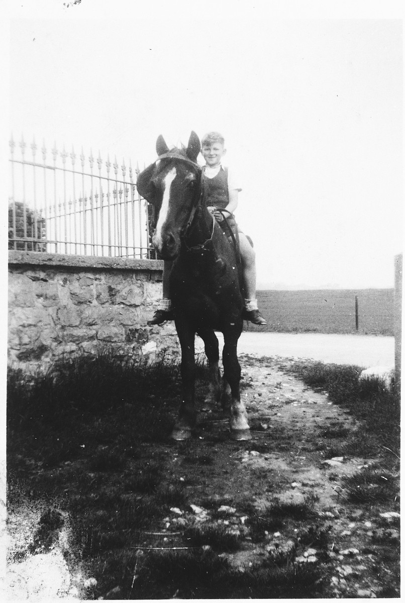 A Jewish child rides a horse on the farm where he was hiding in Dinant, Belgium.

Pictured is Henri Donner.