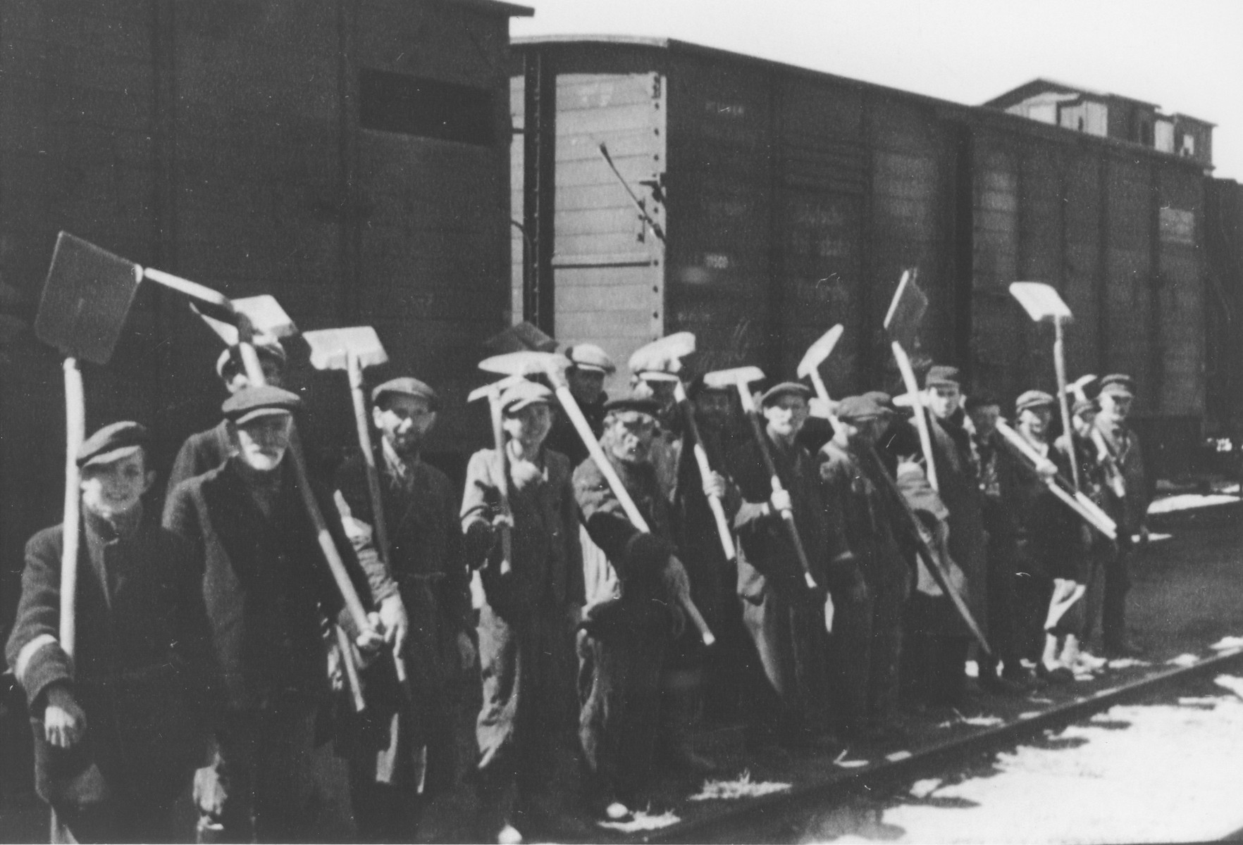 Jewish men and teenagers line-up with shovels in front of a train in an unidentified ghetto.