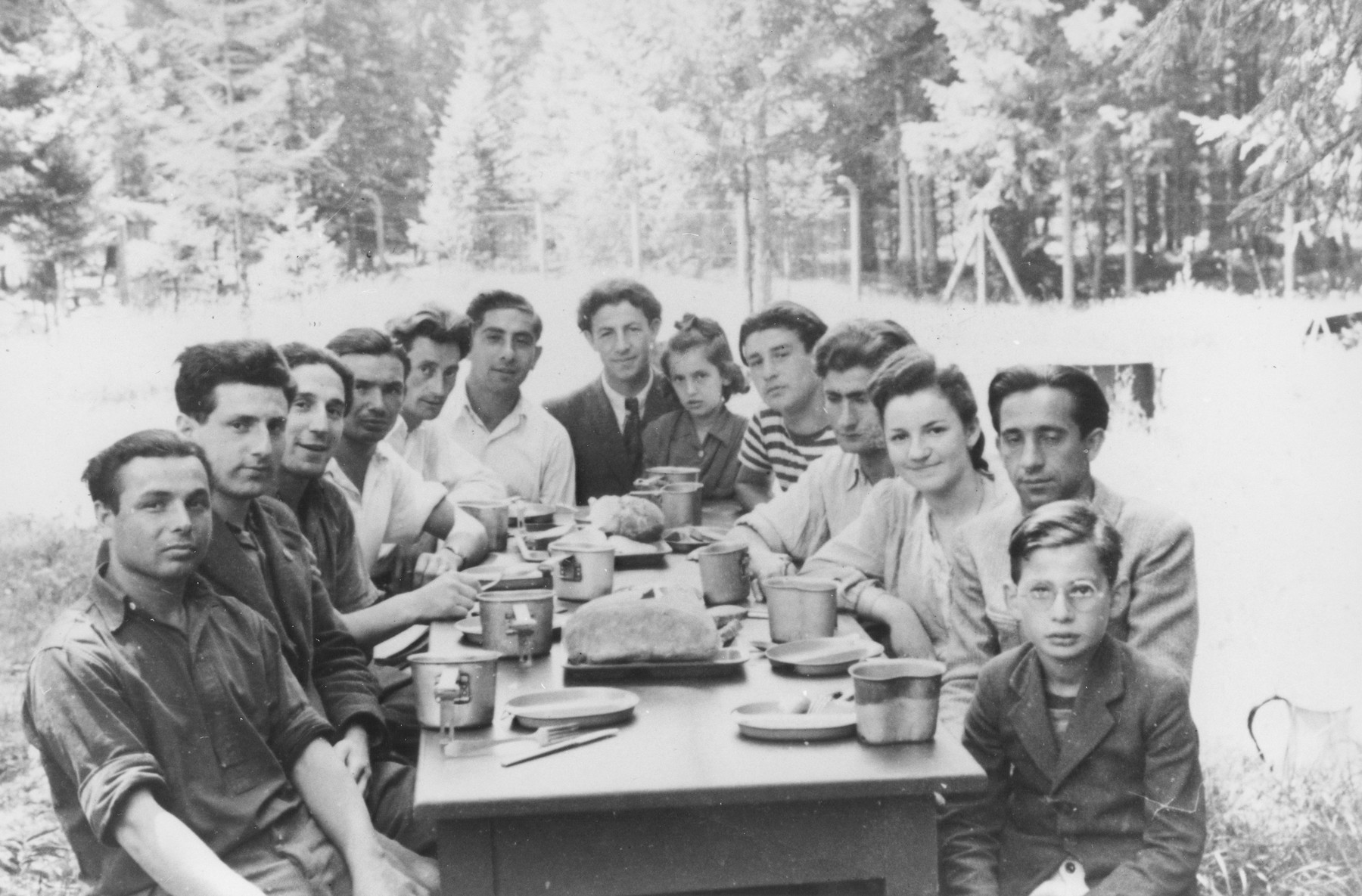 Displaced persons enjoy a meal outside at a school for people with ...