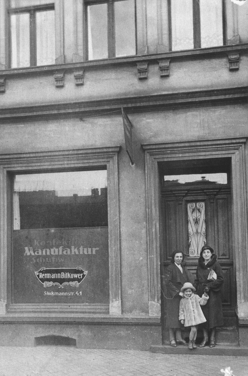 Two women and a child stand outside the entrance to a manufacturing business.