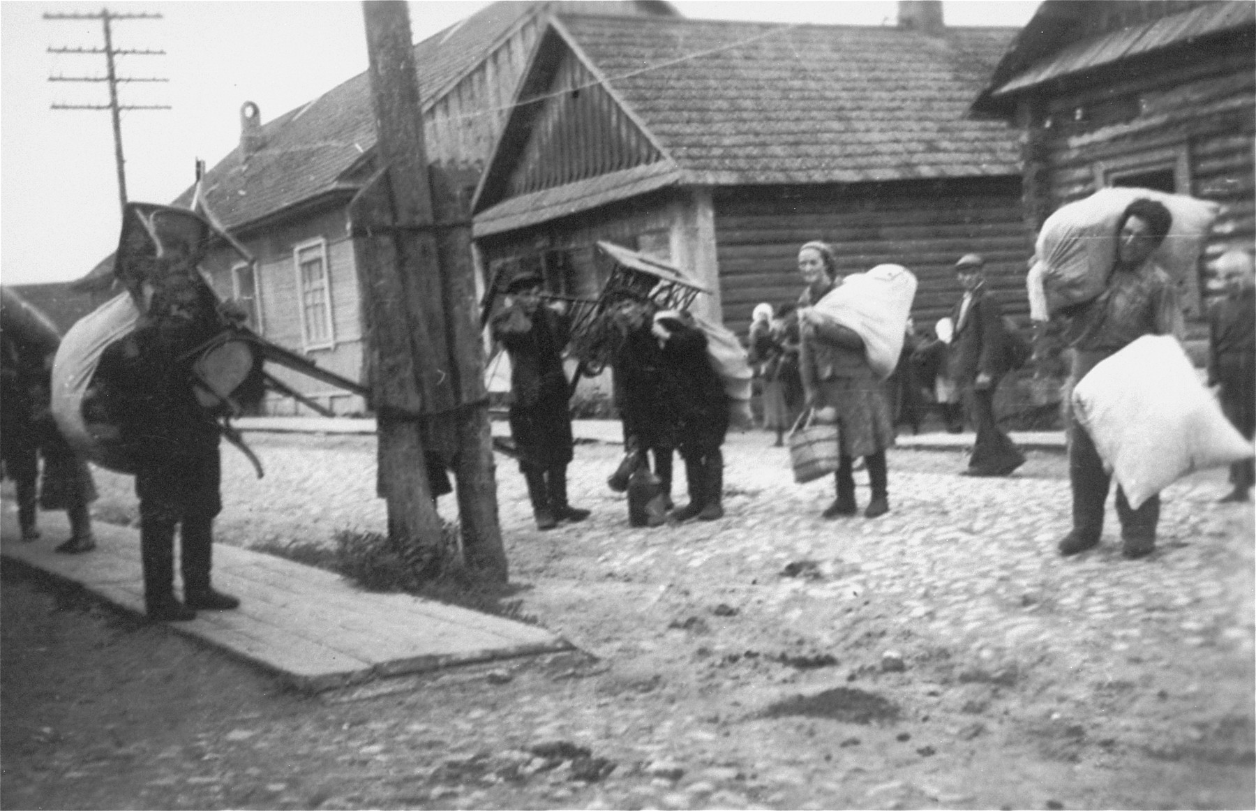 Jews in the Kovno ghetto carry furniture and large bundles.

They are probably moving to new homes following a reduction of the ghetto's borders.