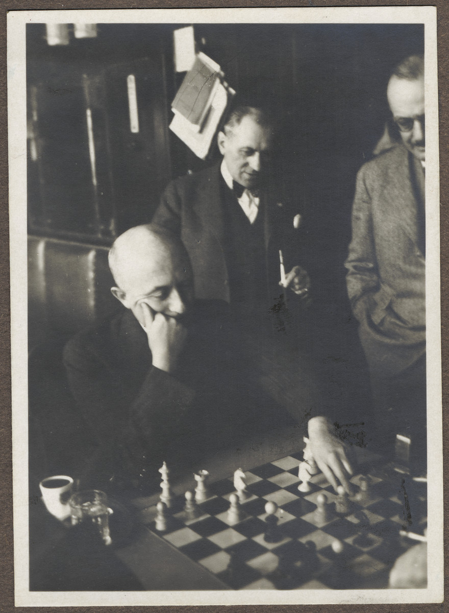 Dr. Karel Kraus plays chess while two friends look on.