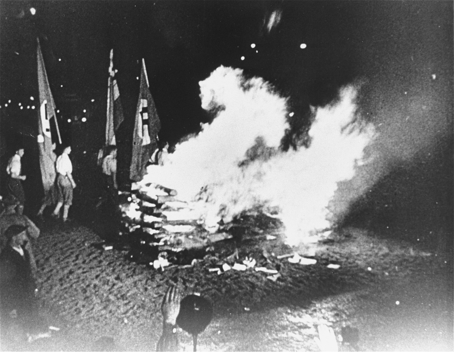 Students carrying Nazi flags march around the bonfire of "un-German" books on the Opernplatz in Berlin. 

Still from a motion picture.