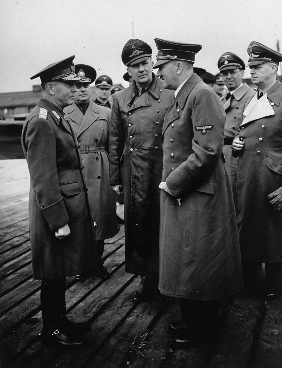 Romanian dictator, Marshal Ion Antonescu (left), converses with Adolf Hitler during an official visit to Germany, as Nazi officials look on.

Pictured in the center is Hitler's interpreter, Paul Schmidt.  Second from the right is Julius Schaub and at the far right, Joachim von Ribbentrop.