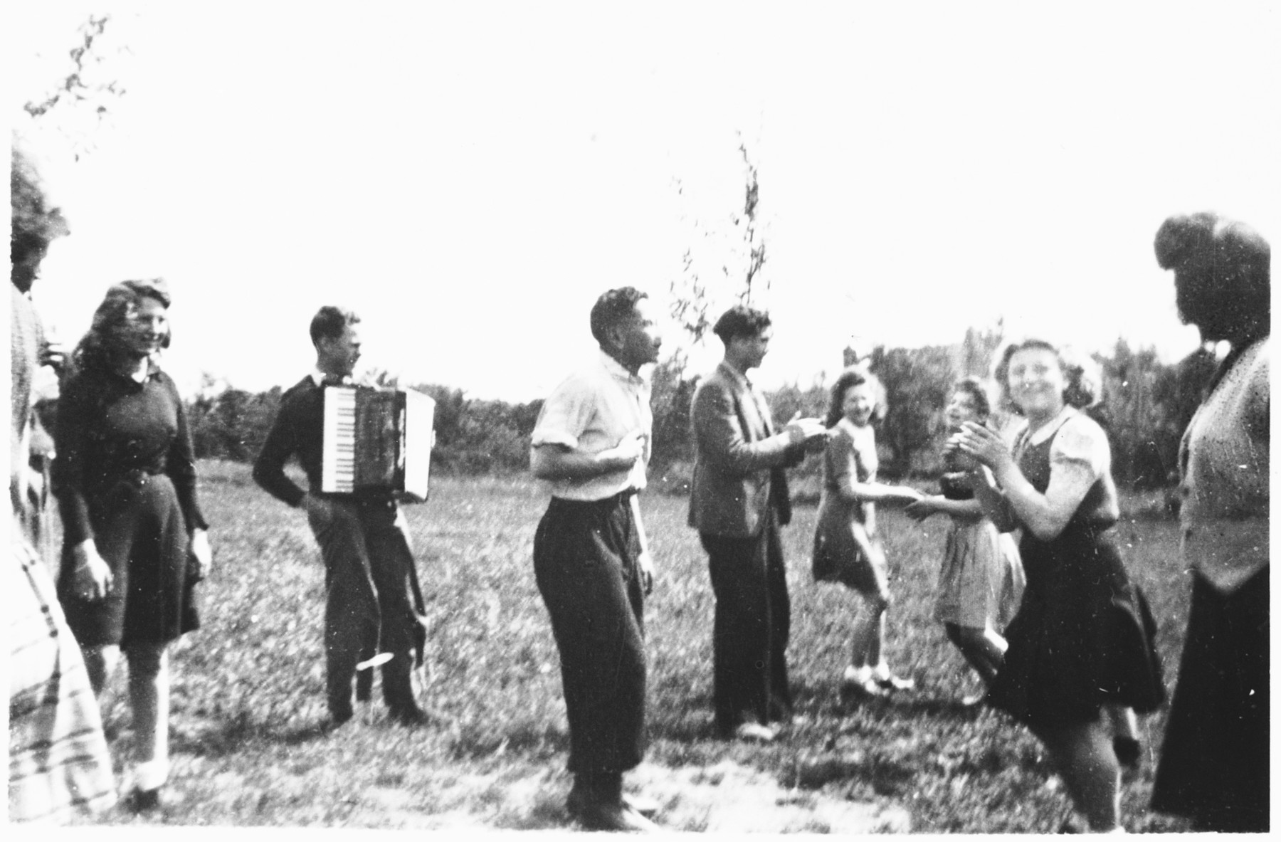 A group of Jewish DP youth dance to an accordion outside the Poulouzat children's home. 

Among those pictured are Herbert Karliner (third from the left in the foreground) and Felix Rosenrib (fourth from the left).