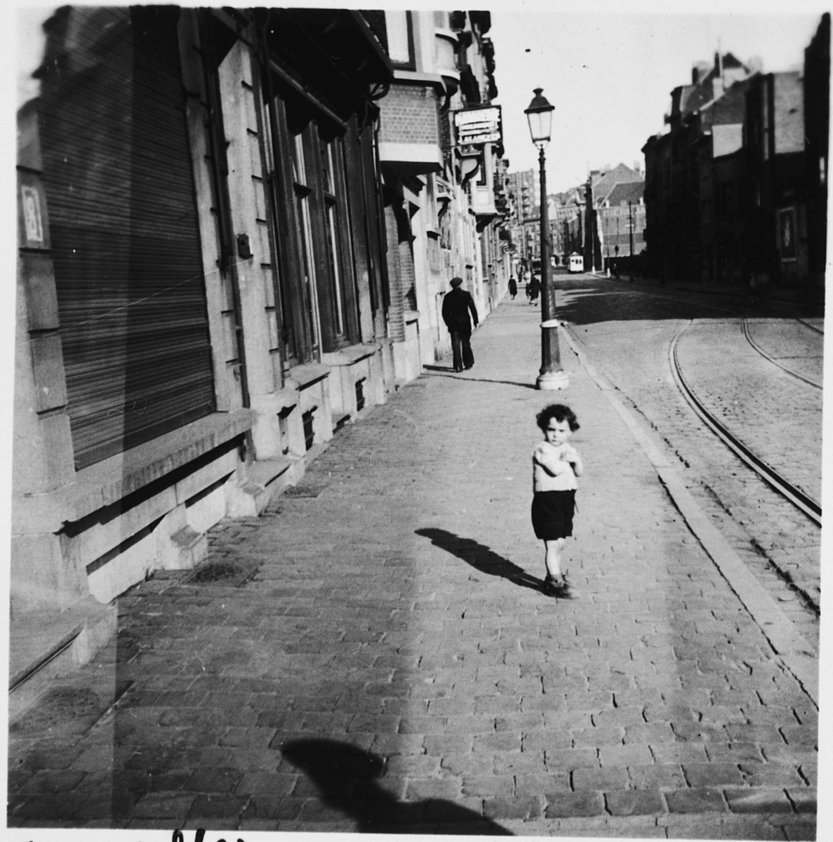 A young Jewish boy poses on a sidewalk in Brussels, near the apartment where he is living in hiding as a Christian with his parents.

Pictured is Nathan (Nounou) Ciechanow.  He was subsequently deported to his death in Auschwitz.