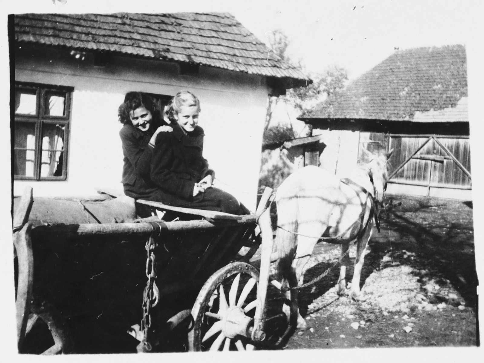 Two Jewish teenagers pose in a horse-drawn wagon in Bilki.

Pictured are Magdalena Mermelstein (left) with her friend, Alice Steinberger (right), outside Magdalena's grandparents' home.