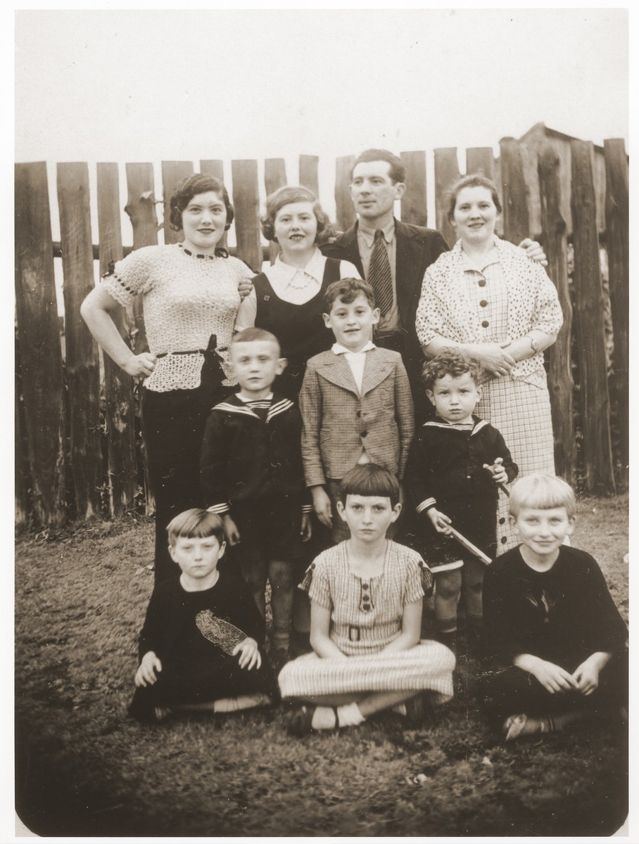 Portrait of the Djament family posing in front of a fence in their yard in Paris.

Standing left to right are Pesl Djament, Sura (Djament) Dresner, Lajb Djament and Rozia (Djament) Goldszmidt.  Standing in the center is Jack Dresner and seated left to right are Fania, Rajzl and Edzia Goldszmidt.