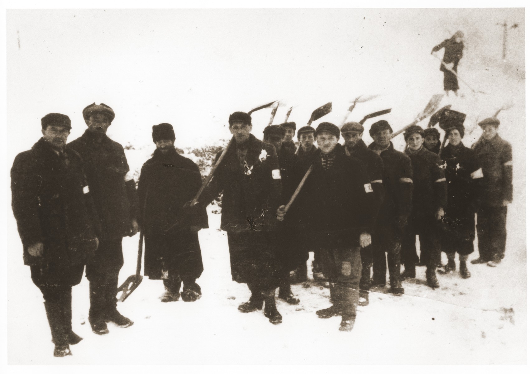 Jewish laborers wearing armbands are forced to shovel snow in Slawkow, Poland.

Chaim Szlojme Imerglik is on the far left. Also pictured is  Joseph Gleitman, the fourth person from the left.