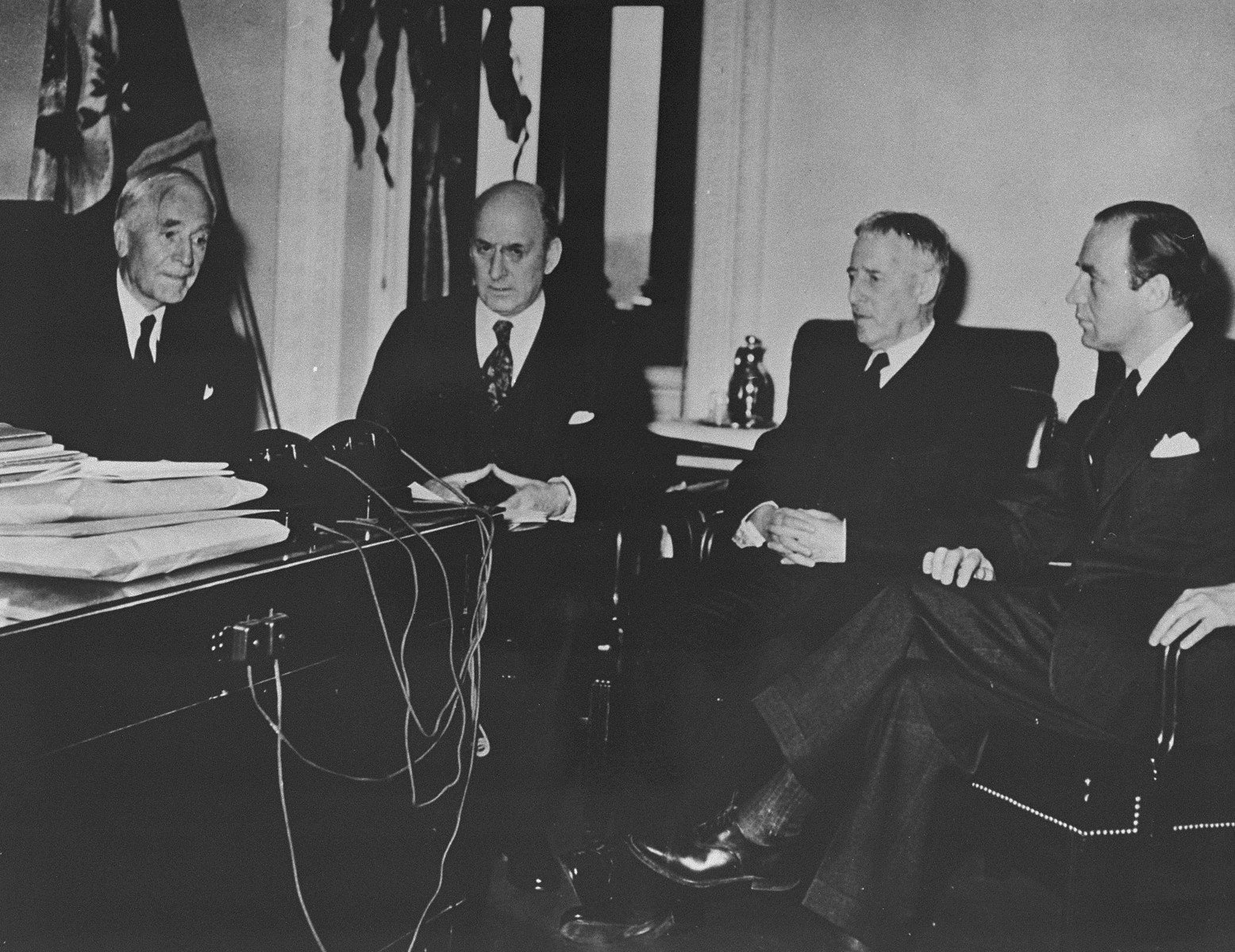Third meeting of the Board of Directors of the War Refugee Board in the office of Secretary of State Cordell Hull. 

Pictured from left to right are: Cordell Hull, Henry Morgenthau, Henry L. Stimson, and John Pehle, Executive Director.
