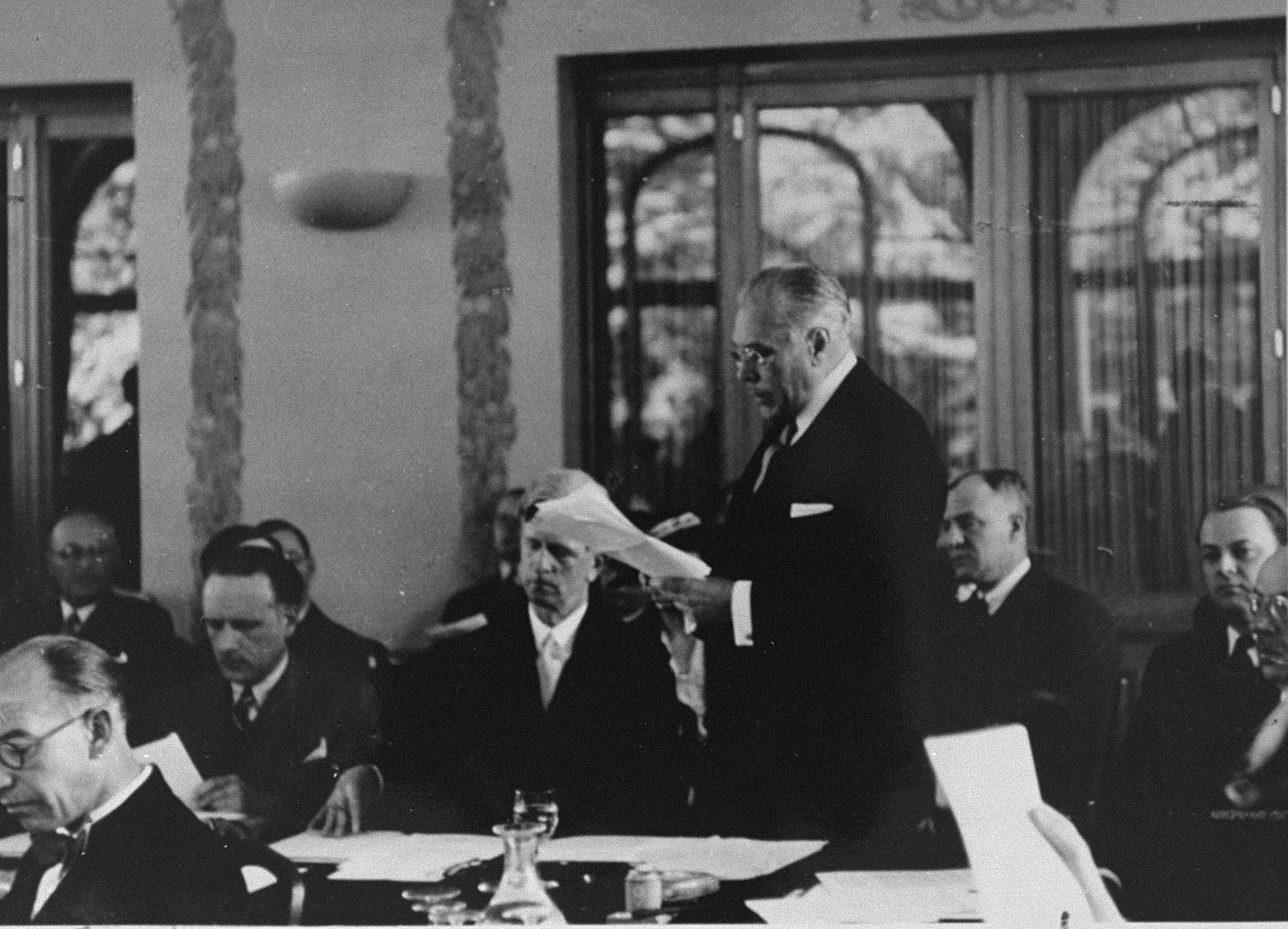 Myron Taylor addresses the International Conference on Refugees at Evian-les-Bains.

James Grover McDonald is seated next to him.  On the far right edge of the picture is Robert Thompson Pell, an assistant to Myron Taylor at State.  The man looking down, second from left of Taylor, with a dark tie and mustache is Georges Coulon.