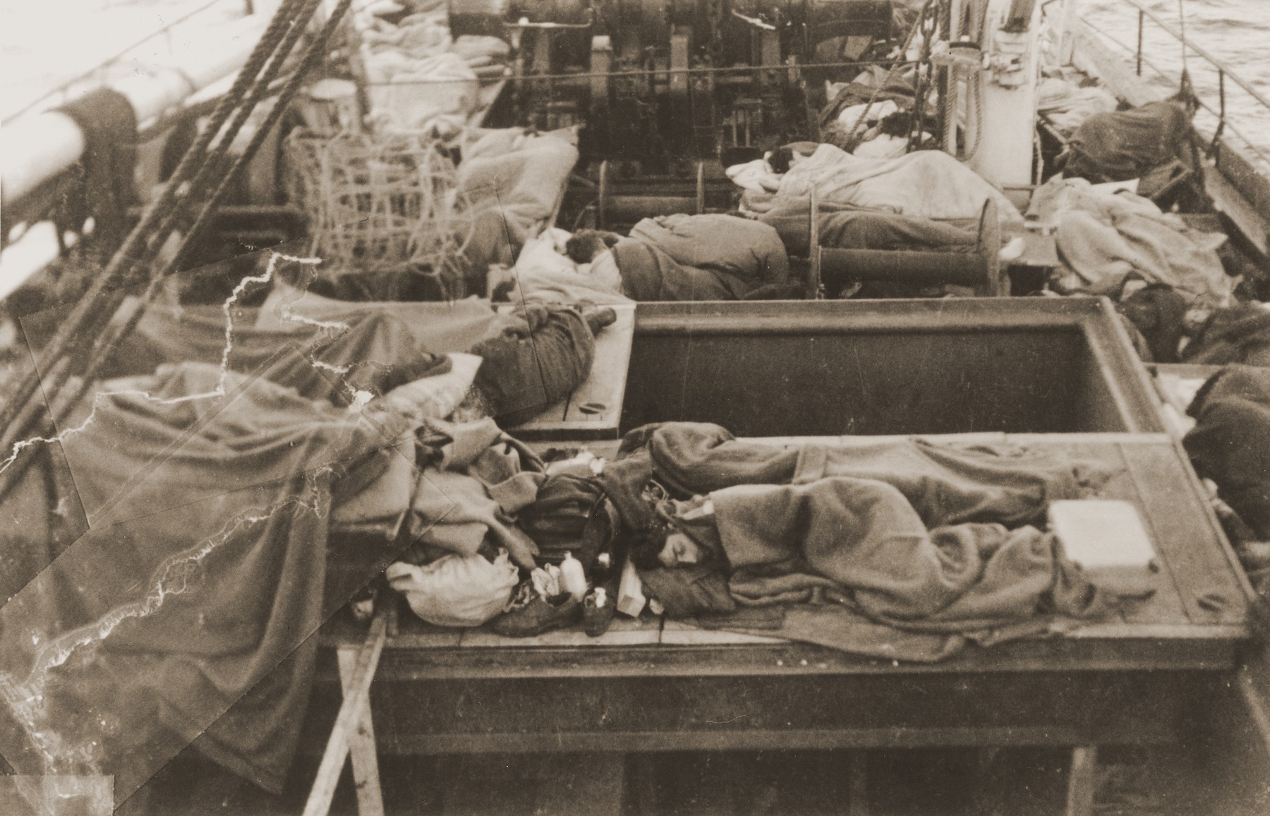 Jewish DPs sleep on the deck of the Mala immigrant ship en route to the new State of Israel.  

Passengers would often come on deck during the night to escape the stench in the hold of the ship.  This photograph was taken just after dawn.