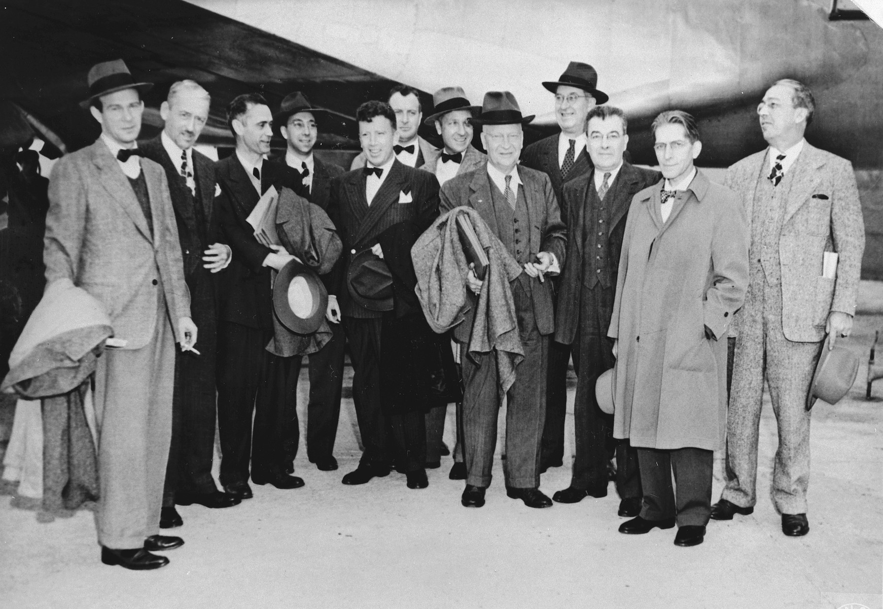 Group portrait of American editors and newsmen who are touring the Zeilsheim displaced persons camp.

The original caption reads, "This is a group photo of the American newsmen and editors that visited the Zeilsheim DP camp in Hanau, Germany. They were reporting on the military government installations and the activities of the US army occupational forces."