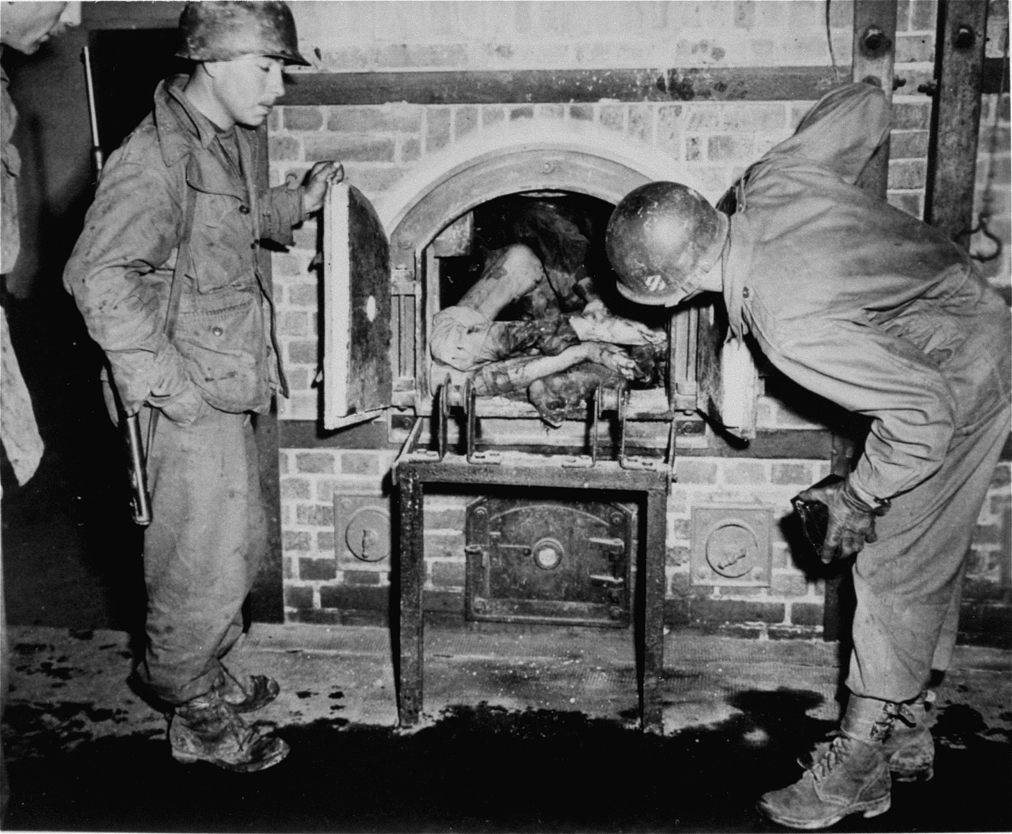 American soldiers inspecting the crematorium in Dachau.  The corpse was put into the ovens after liberation to simulate the operation of the furnace.