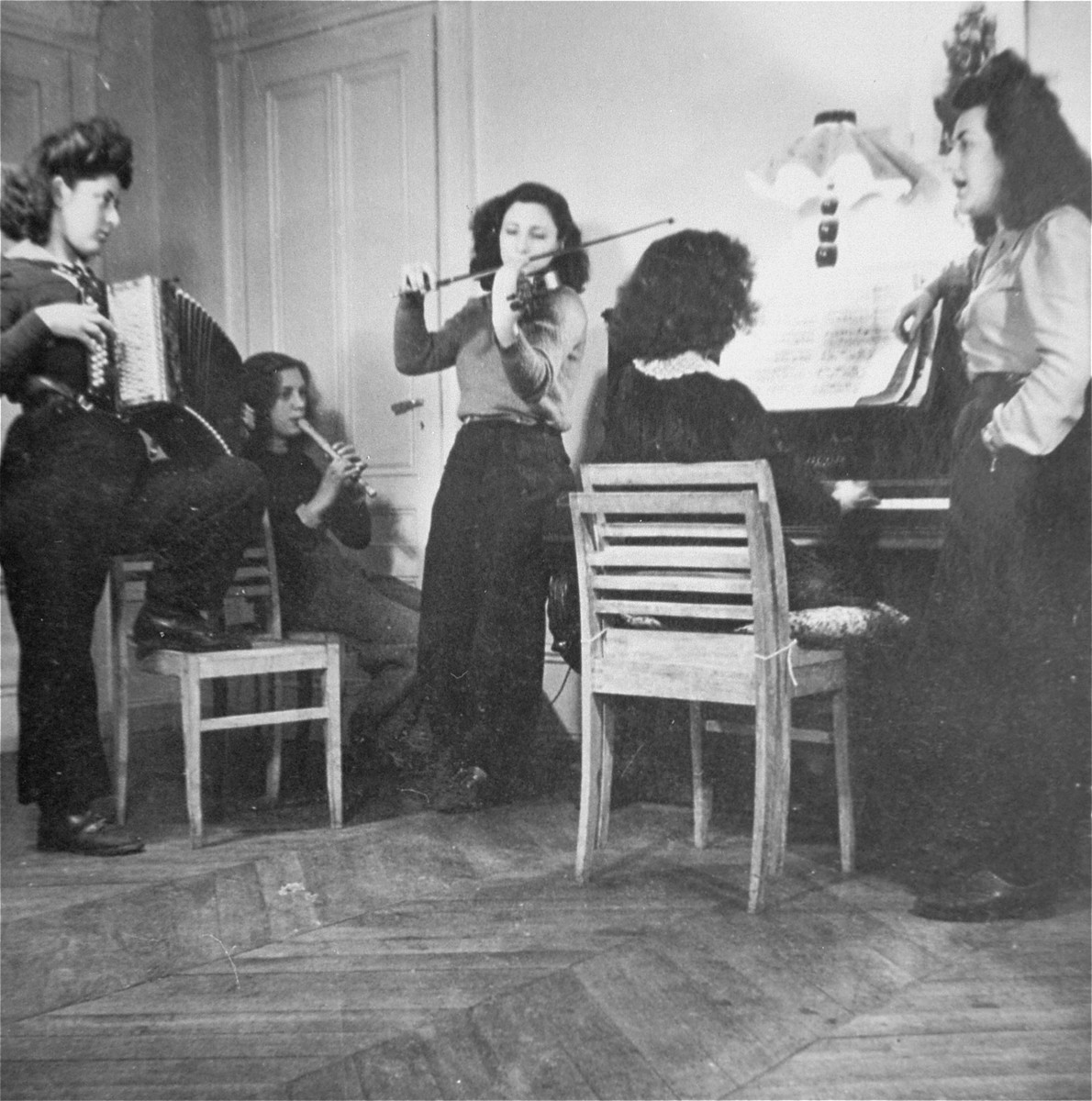 Young Jewish women living at the Le Tremplin children's home perform in a musical ensemble. 

Among those pictured is Paulette Knopp (left, playing the accordian).
