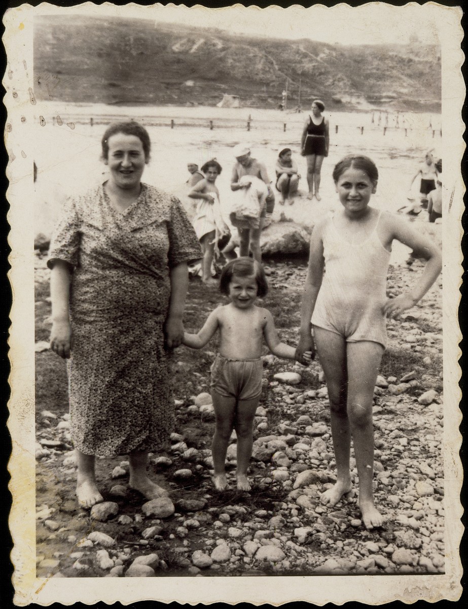 Malka Dugaczanski Zeligman accompanies two young girls to a rocky beach. 

Malka Dugaczanski Zeligman, sister of Rose Dugaczanski Shlanski, is on the left.  Her niece, Hayya Shlanski, is on the right.  The little girl in the center is unknown.  Malka Dugaczanski Zeligman was murdered in Ponar.
