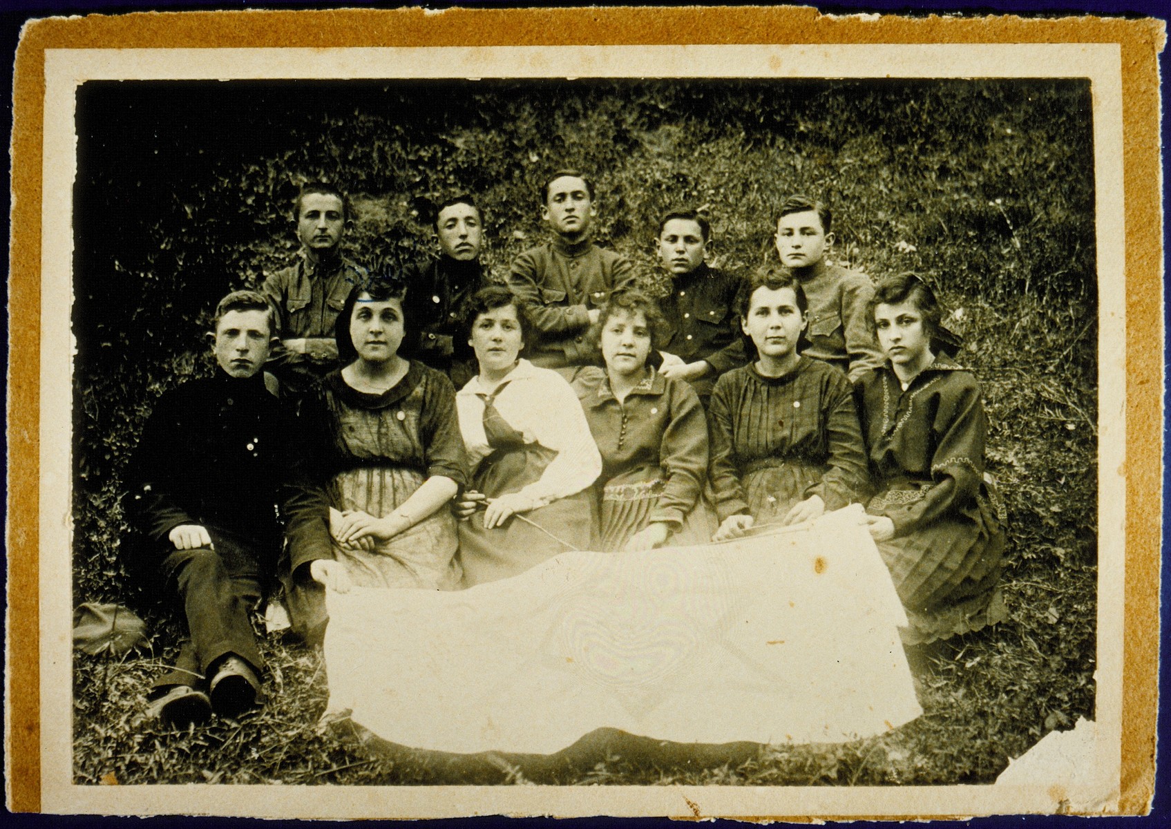 Members of the Zionist group Herut ve-Tehyia (Freedom and Revival) pose in front of the group's banner. 
  
Front row from right to left: Itta-Malka Pachianko, Esther Dwilanski, Zipporah Nochomowicz, Hannah Koppelman, Zipporah Lubetski Tokatli and Shlomo Cofnas.  Top row from right to left: Peretz Kaleko, Shaul Schneider, Zeev Kaganowicz, Shlomo Kiuchefski and Shalom Sonenson.  

Zipporah Lubetski Tokatli, Hannah Koppelman, Shaul Schneider and Peretz Kaleko immigrated to Palestine. Zipporah Nochomowicz immigrated to South America.  Shalom Sonenson  survived the Holocaust in hiding.  Itta-Malka Pachiano was murdered during the Holocaust.  Shlomo Kiuchefski was murdered by members of the Polish Home Army.