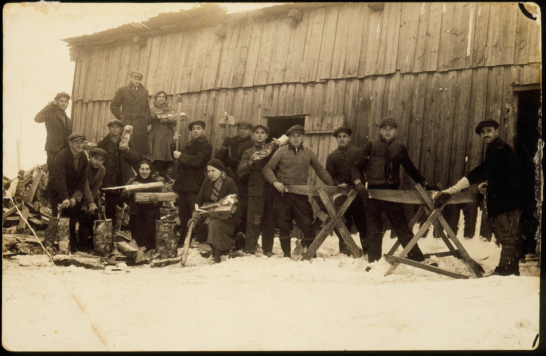 Members of the Hehalutz hachshara in Oszmiana saw wood in the lumberyard.