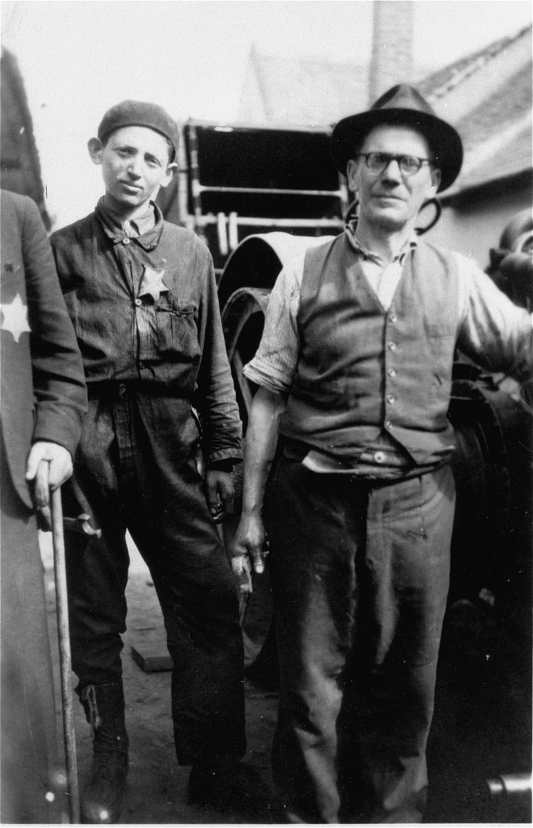 A father and son, wearing a Jewish badge, in front of their machine shop in the Debrecen ghetto.

Pictured are Moritz and his son Endre Goldstein.  Moritz and Matilde Goldstein had four sons, Alex (b. 1914), Ernst (b. 1918), Miklos (b. 1920), and Endre (b. 1928).  Moritz died while serving in a Hungarian labor brigade. In April 1944, Matilde, Ernst and Endre were deported to Auschwitz, where the mother and her youngest son were gassed immediately.  Ernst was imprisoned for a time in Auschwitz before being sent to a series of concentration camps in Germany.  He survived the camps and eventually emigrated to the U.S. in 1946.