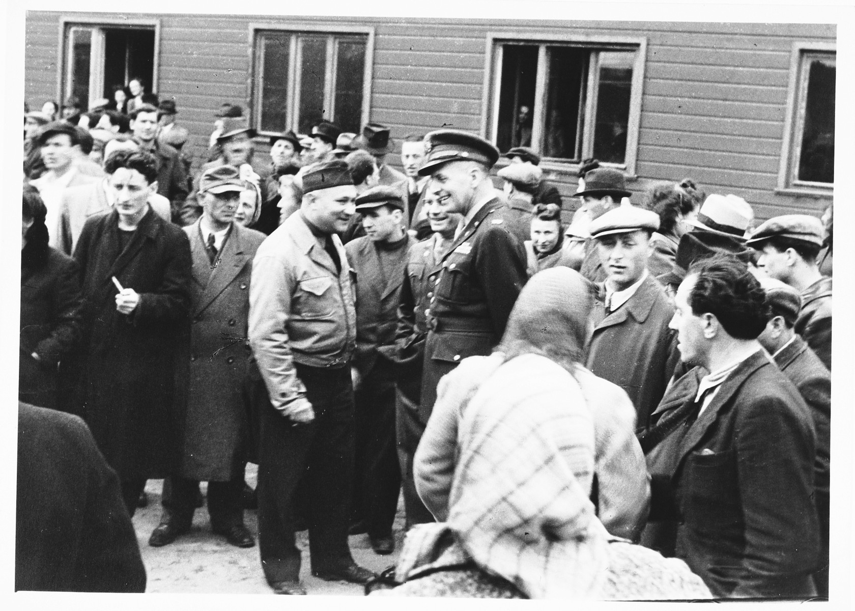 UNRRA camp director, Harold Fishbein (in the light jacket), converses with an American military officer amid a crowd of Jewish DPs outside a barracks in the Schlachtensee displaced persons camp.  

Moise Finkelsztajn is on the right.