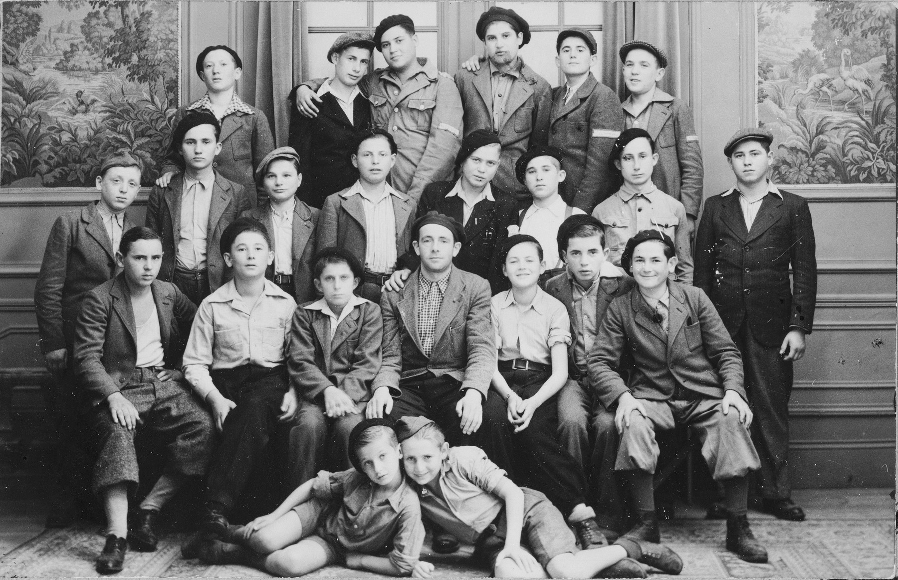 Group portrait of Jewish DP youth who numbered among the Buchenwald children, at an OSE (Oeuvre de Secours aux Enfants) children's home in France [either in Ambloy or Taverny].

The man in the middle is Leo Margolis, a German Jew who was in Buchenwald for approximately six years and helped care for the children.  To his left is Natan Swarc from Piotrkow and on the far right of that row is Josef Szwarcberg.  Lying in front are Izio Rosenman and Jacques (Jakob) Finkelsztajn.