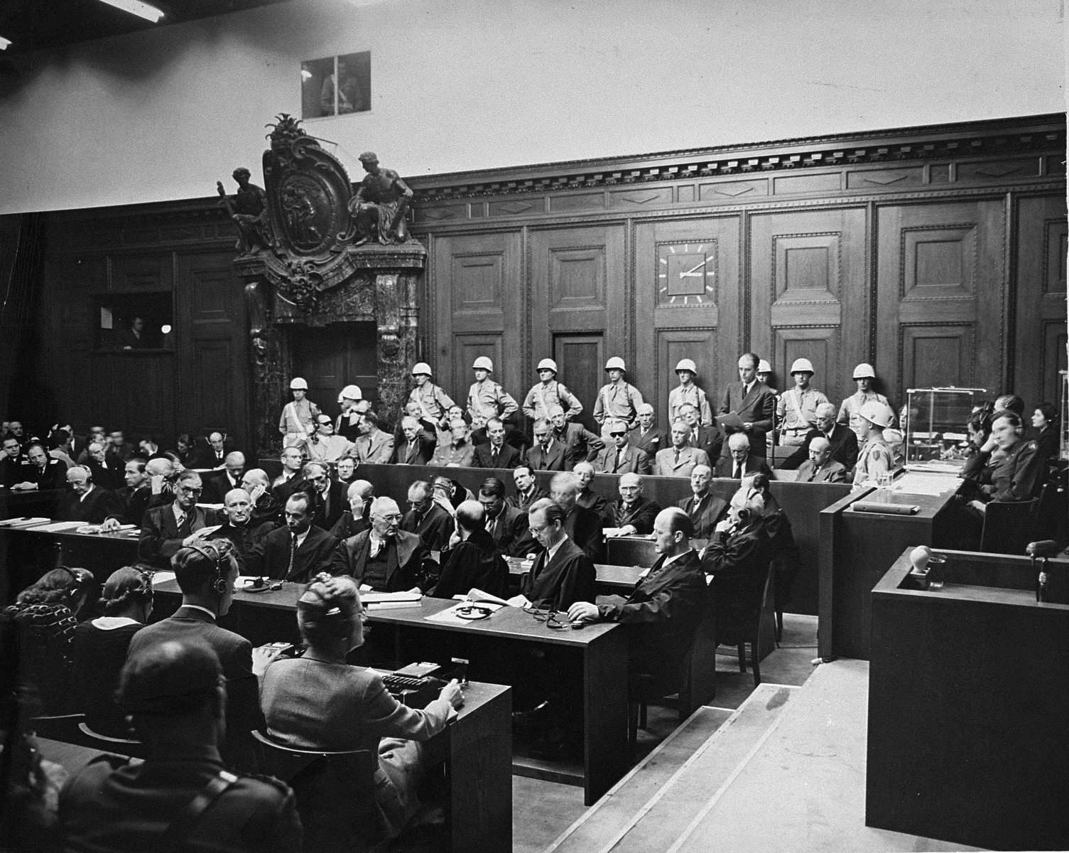 The defendants and their lawyers at the International Military Tribunal trial of war criminals at Nuremberg.  Defendant Albert Speer (standing at right) delivers a statement in the dock.