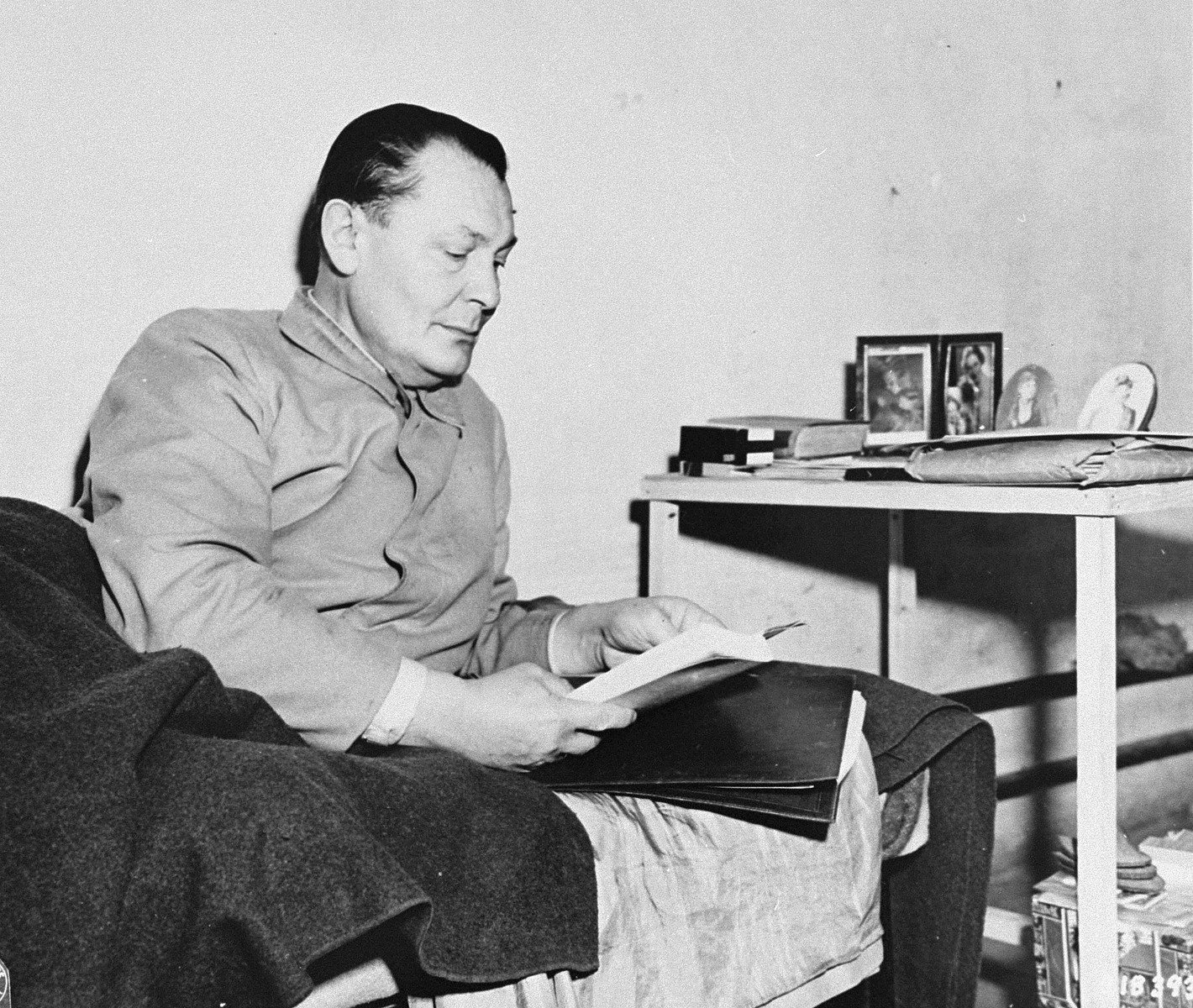 Defendant Herman Goering lies in his bunk in jail during the International Military Tribunal trial of war criminals at Nuremberg.  On his writing table are pictures of his family which he objected to having photographed.