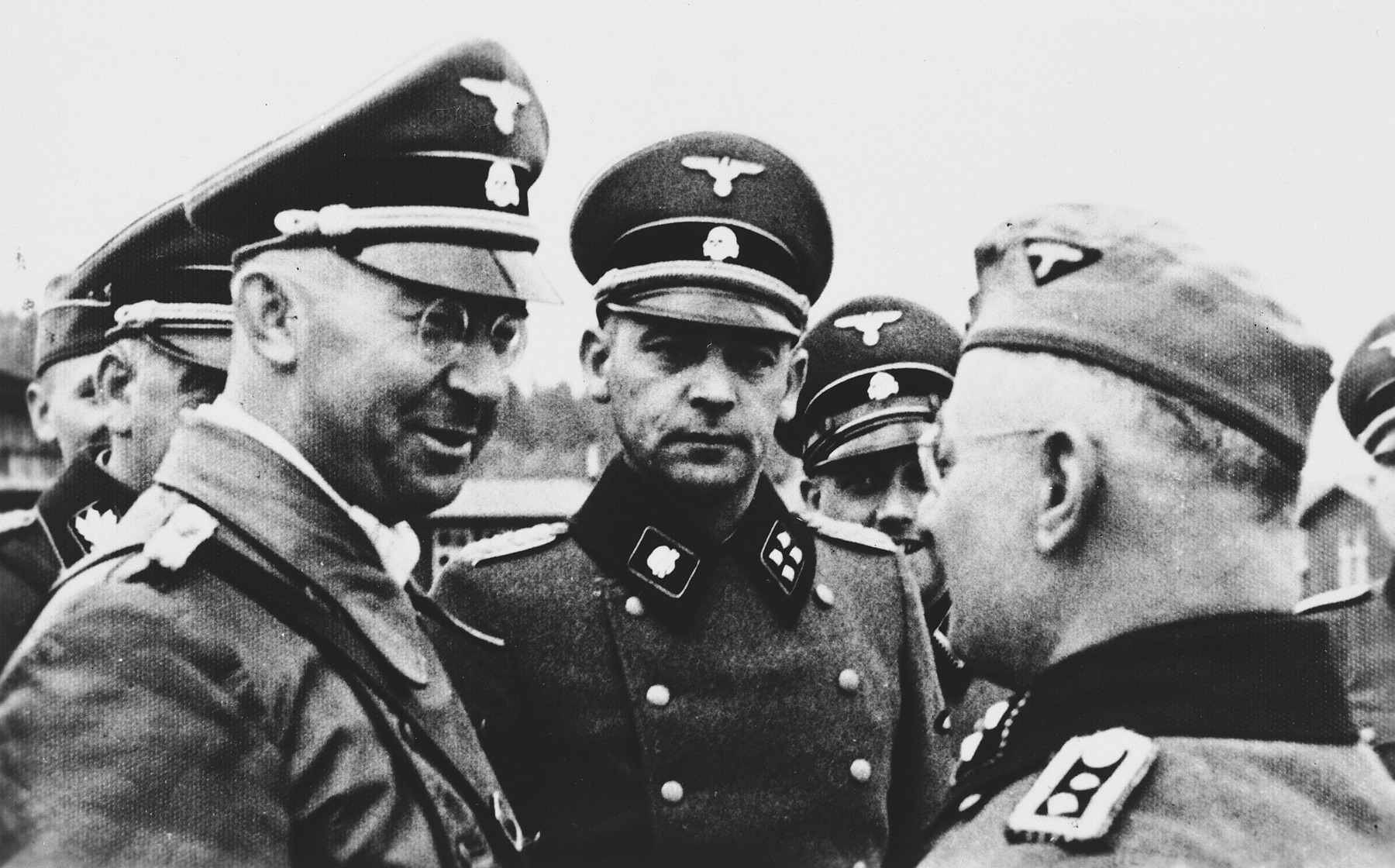 Heinrich Himmler confers with SS officers while visiting the Flossenbuerg concentration camp.

Heinrich Himmler is pictured on the left.  To his right the camp commandant Karl Künstler, to the his right in the back the adjutant Ludwig Baumgartner.