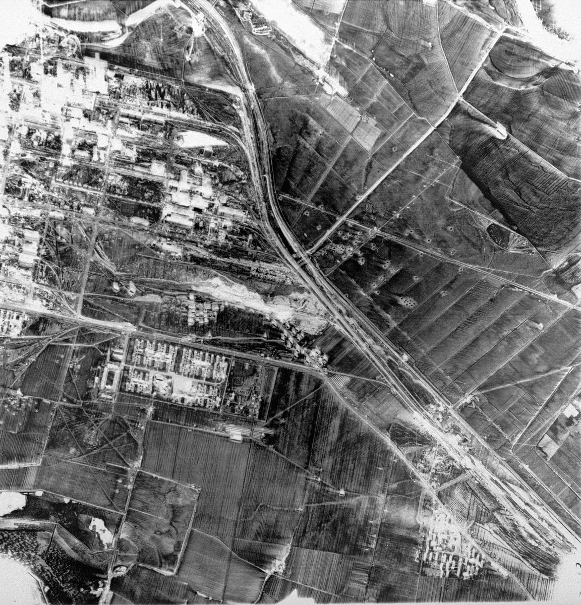 An aerial reconnaissance photograph showing the I.G. Farben complex.  [oversized photo] 

Pictured here: IG Farben plant (top), Auschwitz III Buna (Monowitz) camp (left) and slave labor camp fno 5 (right).