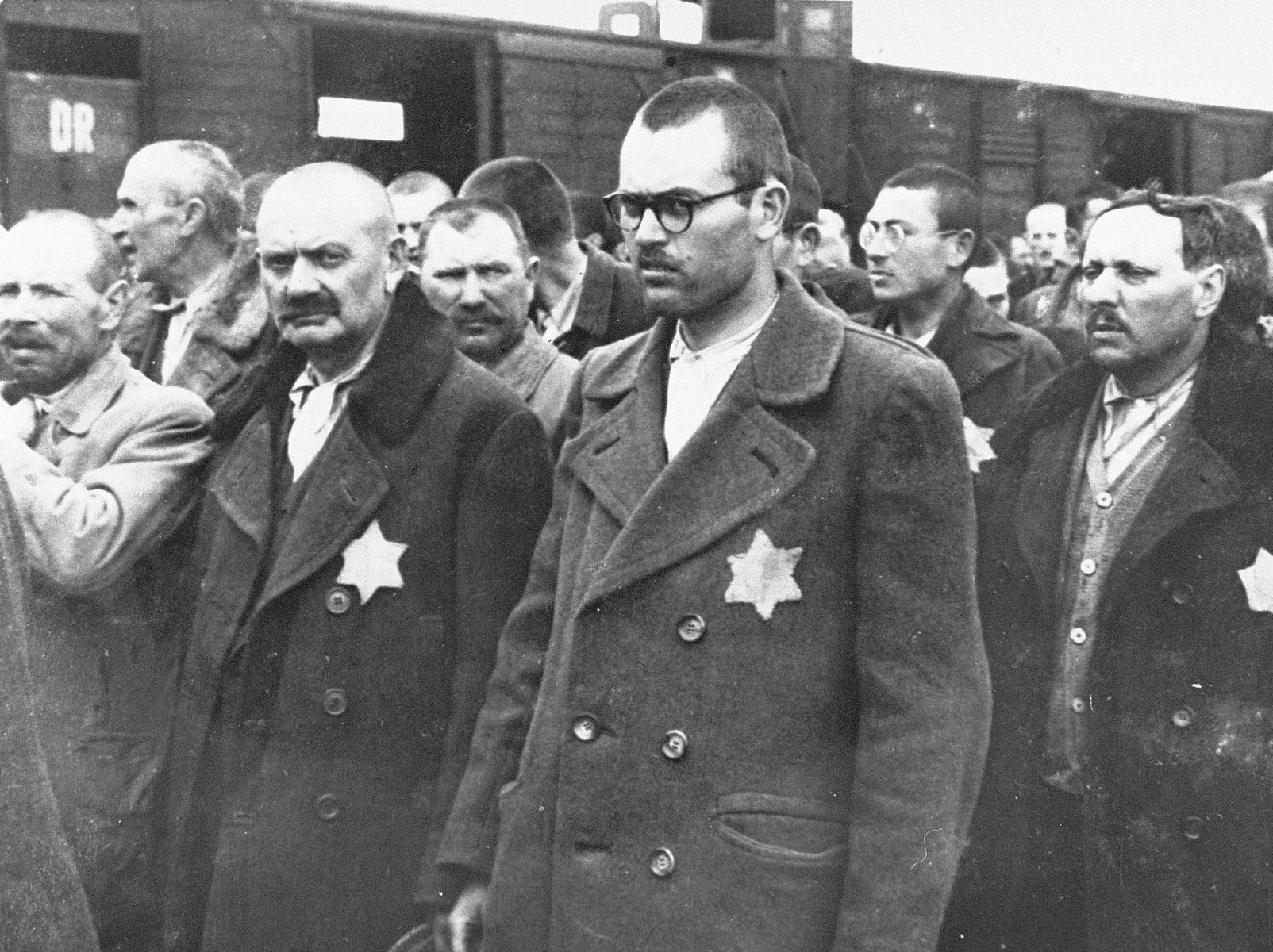 Jewish men from Subcarpathian Rus await selection on the ramp at Auschwitz-Birkenau.

Among those pictured are Menachem Zvi Fettman (center, in glasses) from Nyirjespuszta and his father, Yaakov Fettman (left).