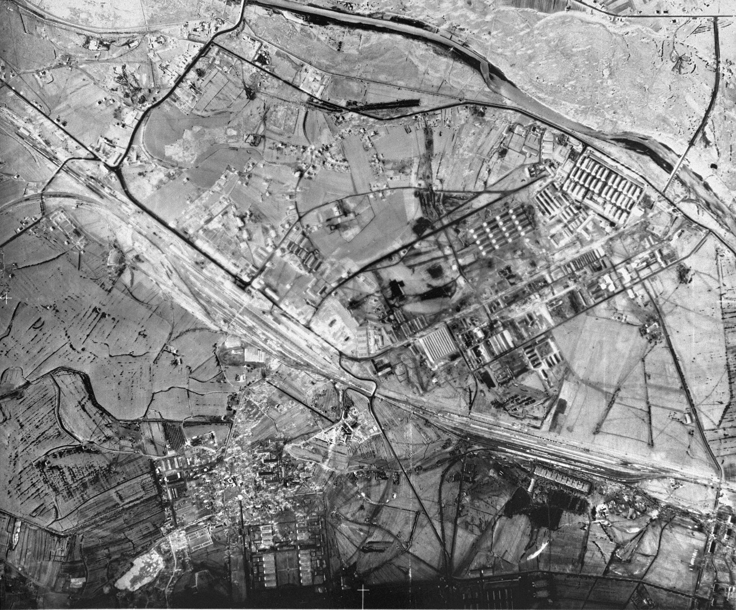 An aerial reconnaissance photograph of Auschwitz I showing the prisoners' barracks and administrative buildings which are visible along with the main railway lines.