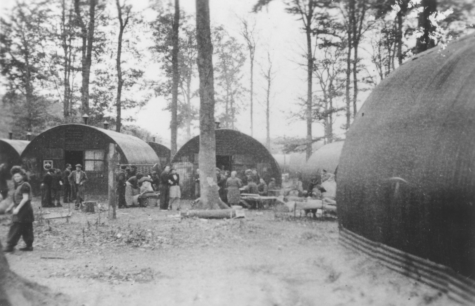 Former passengers on the Exodus 1947 gather outside a row of Nissen huts in the Poppendorf displaced persons camp.