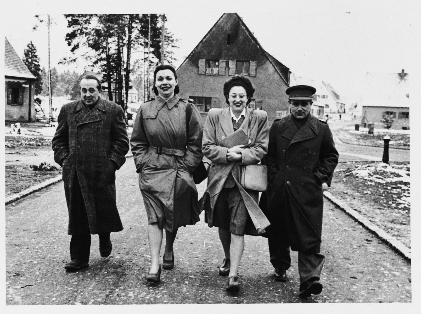 Two men and two women walk down a snow-dusted lane in the Foehrenwald DP camp.