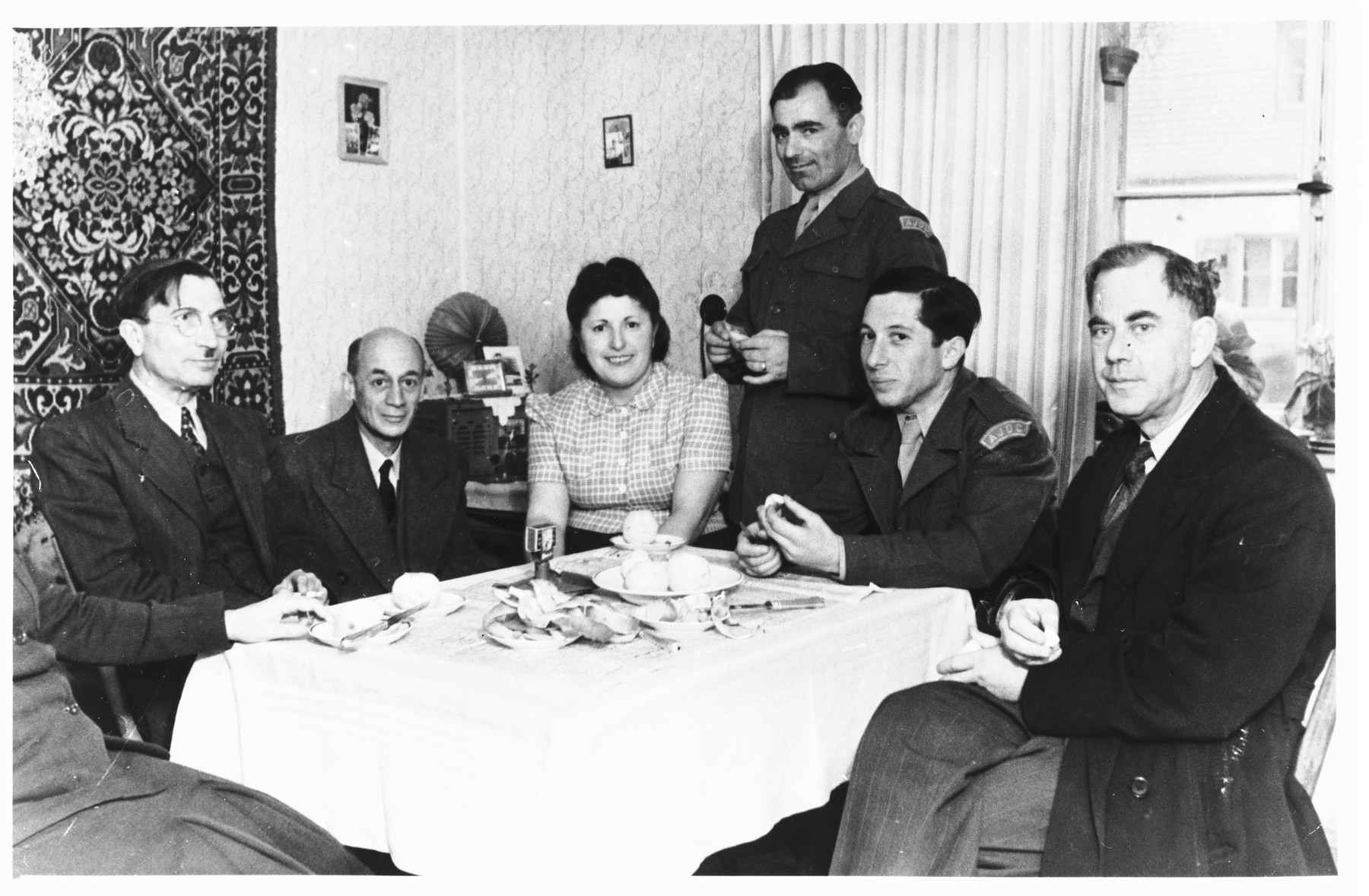 Issak and Fira Libstug entertain guests around their dining room table in the Foehrenwald DP camp.

Issak Libstug and one of his guests are wearing AJDC uniforms.