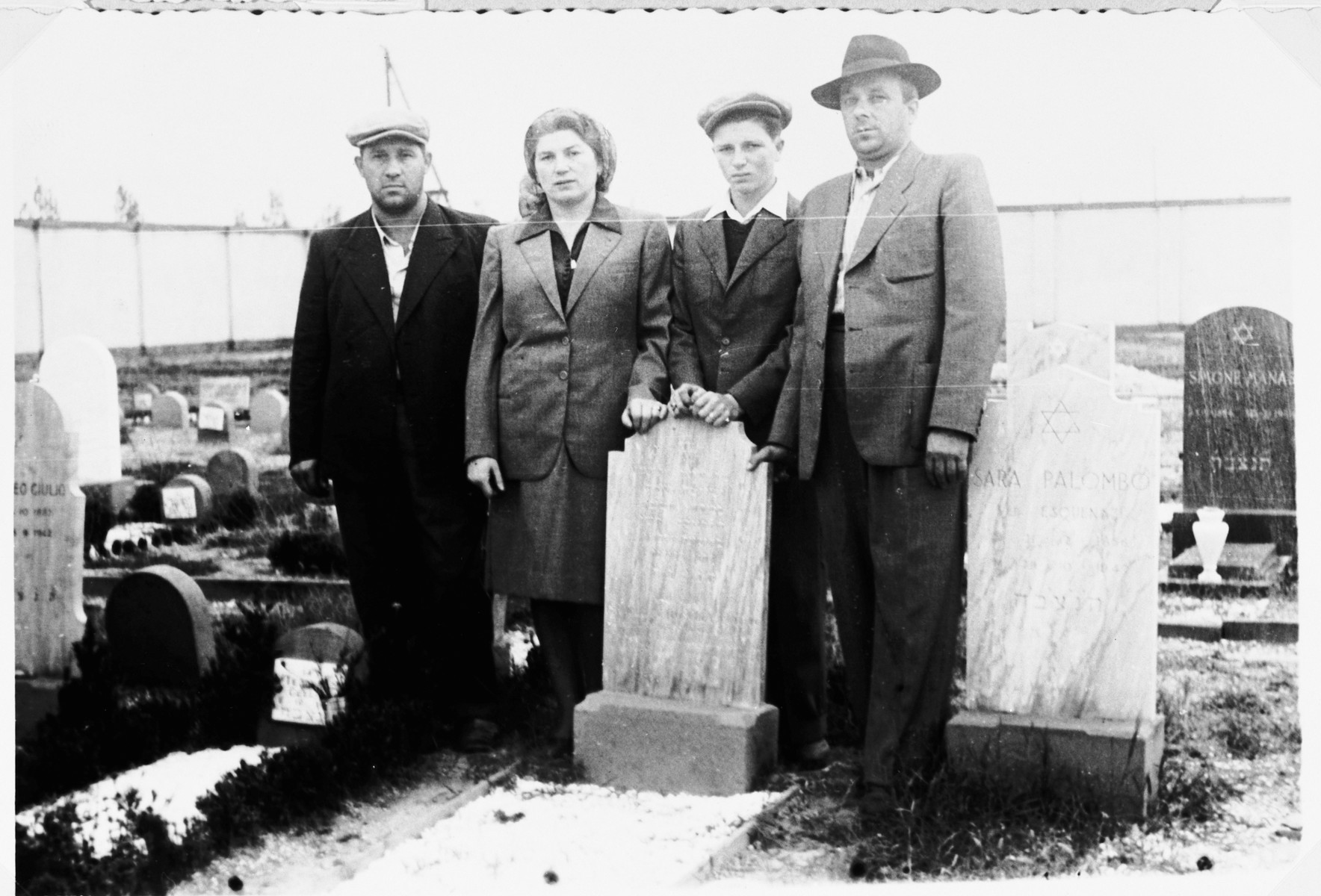 Henia and Shie Zoltak pose next to the grave of their husband and father.

Two friends stand on either side.  On the left os Hersh-Leib Smobuk and on the right is "Pelte".