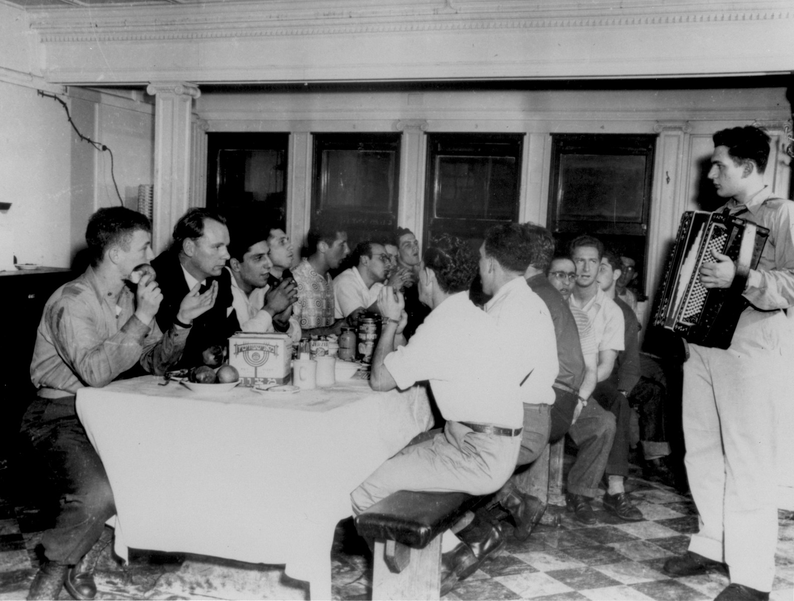 The crew of the Exodus 1947 attends a Passover seder in the ship's mess while en route from the United States to Europe.

The accordian player is William (Vevie) Siegel.  Pictured to the left of the accordian player are Al Naftel and Murray Aronoff.  On the left side of the table, the first four crew members from left to right are: Bentley Forman, John Grauel, Dov Mills and Avraham Siegel.  Pictured seated second from the left is Donald Molofsky, an American crewmember on the Exodus.