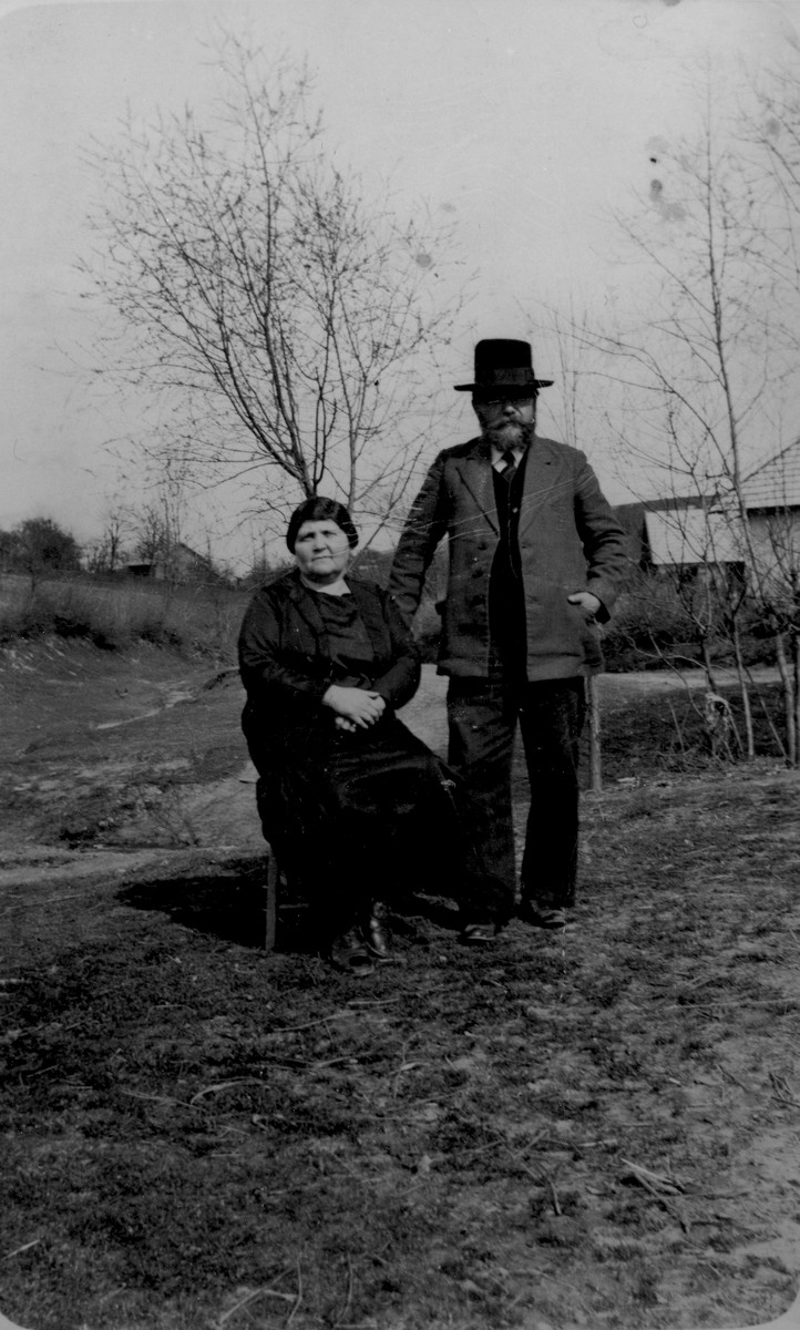 An elderly Jewish couple poses outside their home in Pruchnik, Poland.

Pictured are Lejzer and Chana (Taubenfeld) Gurfein.
