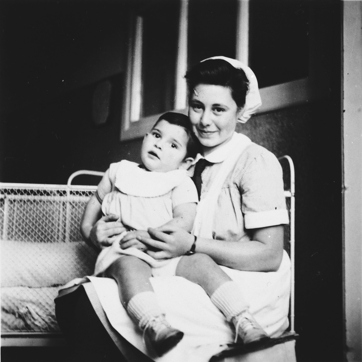 A Jewish refugee youth cares for a young child while training to become a pediatric nurse in Switzerland.

Pictured is Ilse Wulff (right).