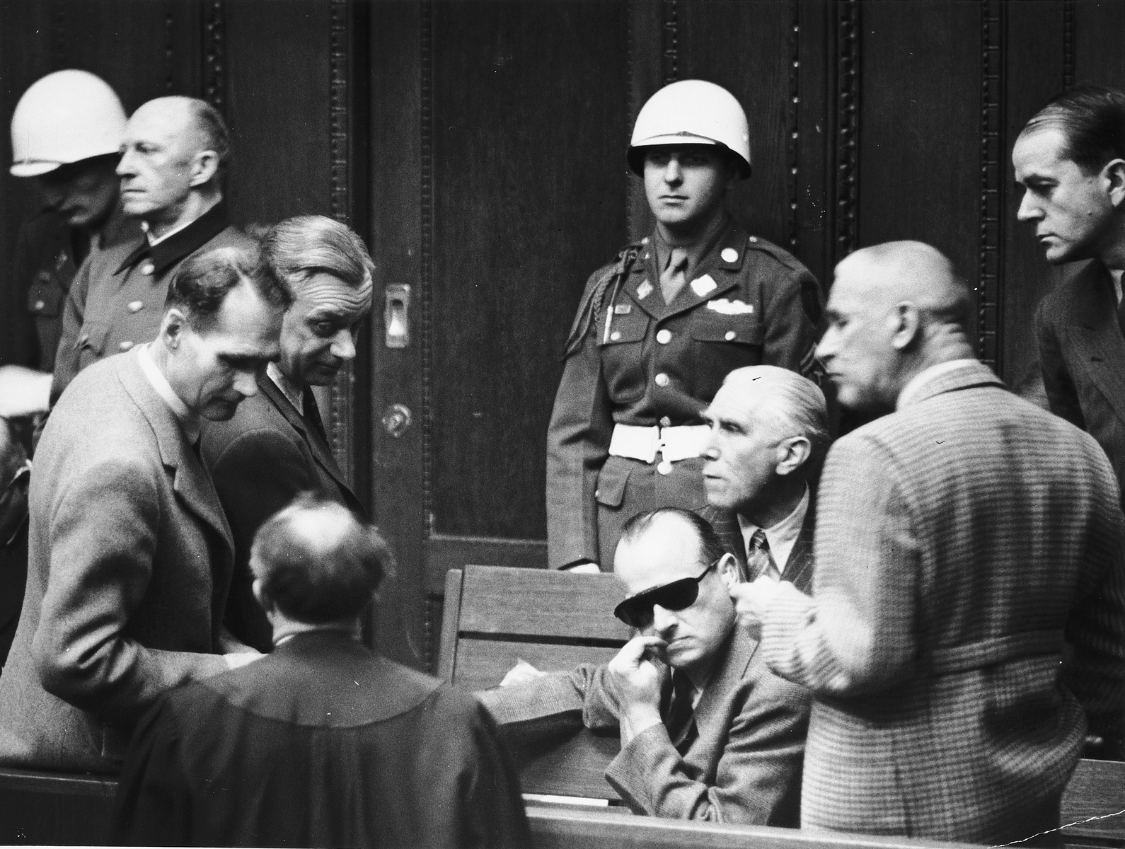 Defendants talk to each other and to their lawyer during a break at the International Military Tribunal in Nuremberg. 

Among those pictured from left to right are Rudolf Hess, Arthur Seyss-Inquart, Hans Frank, Franz von Pappen, Wilhelm Frick and Albert Speer.  General Alfred Jodl is standing in back on the far left. Also pictured standing in the back, center is the donor, the American military policeman, Albert Rose.