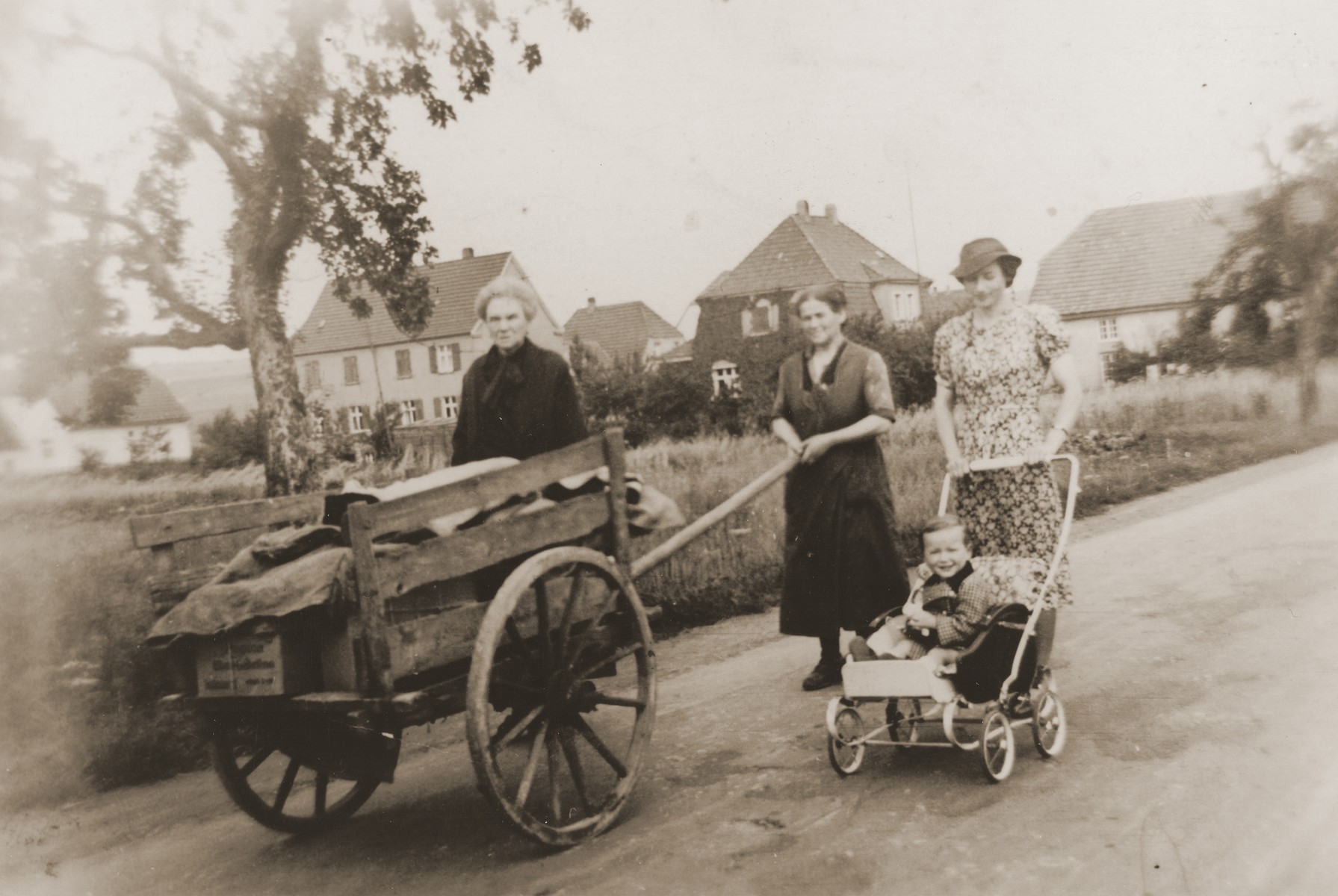 Mathilde Stern walks down a Willebadessen street with her sister-in-law, Rosa Stern (pushing cart), and daughter-in-law, Resi Markhoff Stern, who is pushing her son, Manfred, in a stroller.