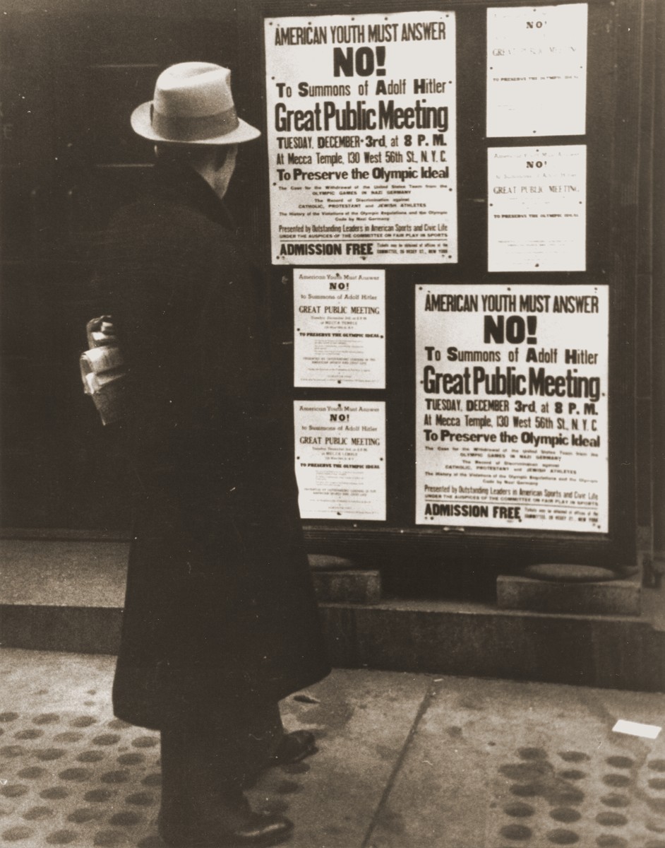 A pedestrian reads a notice announcing an upcoming public meeting, scheduled for Tuesday, December 3 at the Mecca Temple in New York City, to urge Americans to boycott the 1936 Berlin Olympics.

The meeting was presented by "Outstanding Leaders in American Sports and Civic Life" under the auspices of "The Committee on Fair Play in Sports."