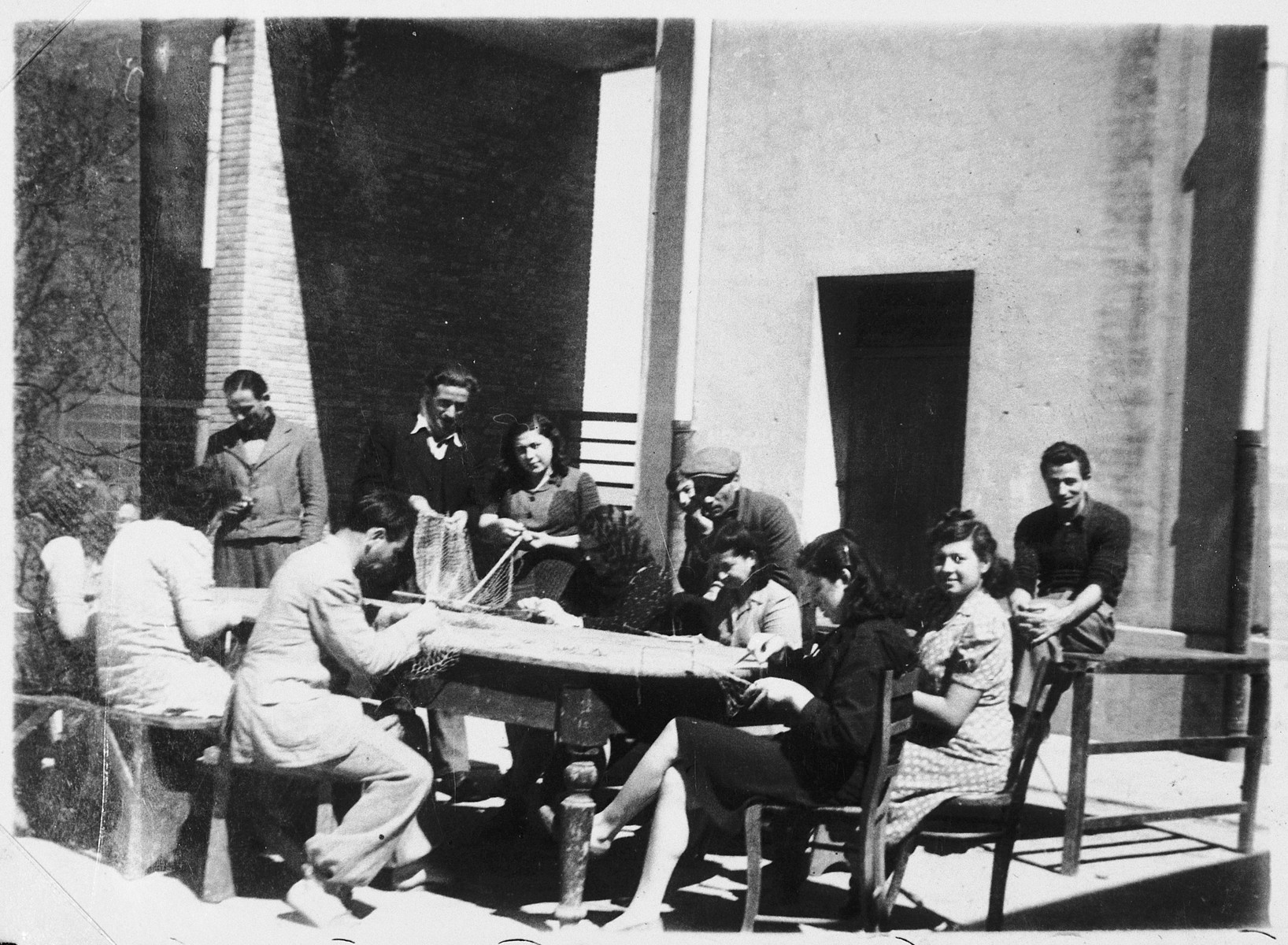 Jewish DPs weave fishing nets at the Migdalor hachshara, a maritime Zionist collective in Fano, Italy.

Among those pictured are: Carola Shlomovitz (standing in the center), and Sara Faitlovitz (foreground, right).