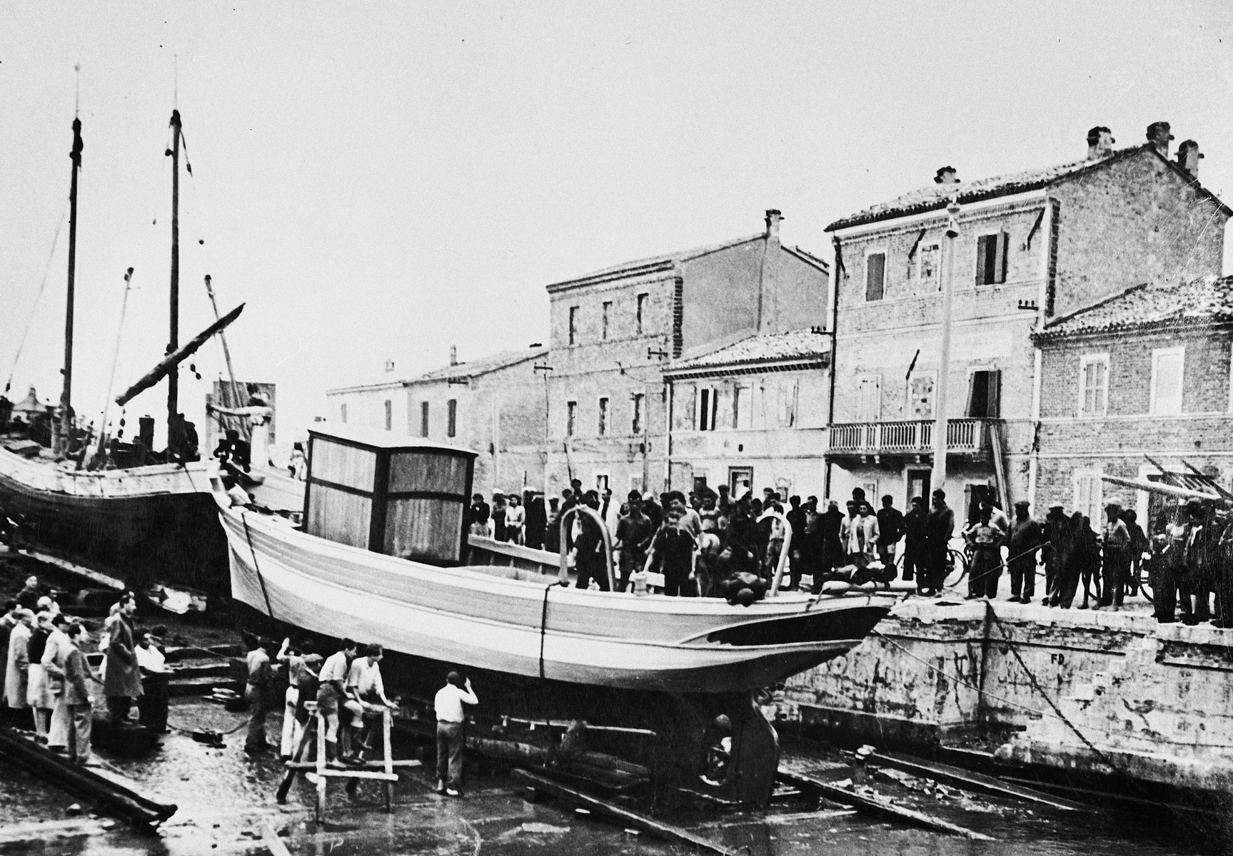 Jewish DPs gather on the pier alongside their newly constructed fishing boat during its christening ceremony at the Migdalor hachshara, a maritime Zionist collective in Fano, Italy.