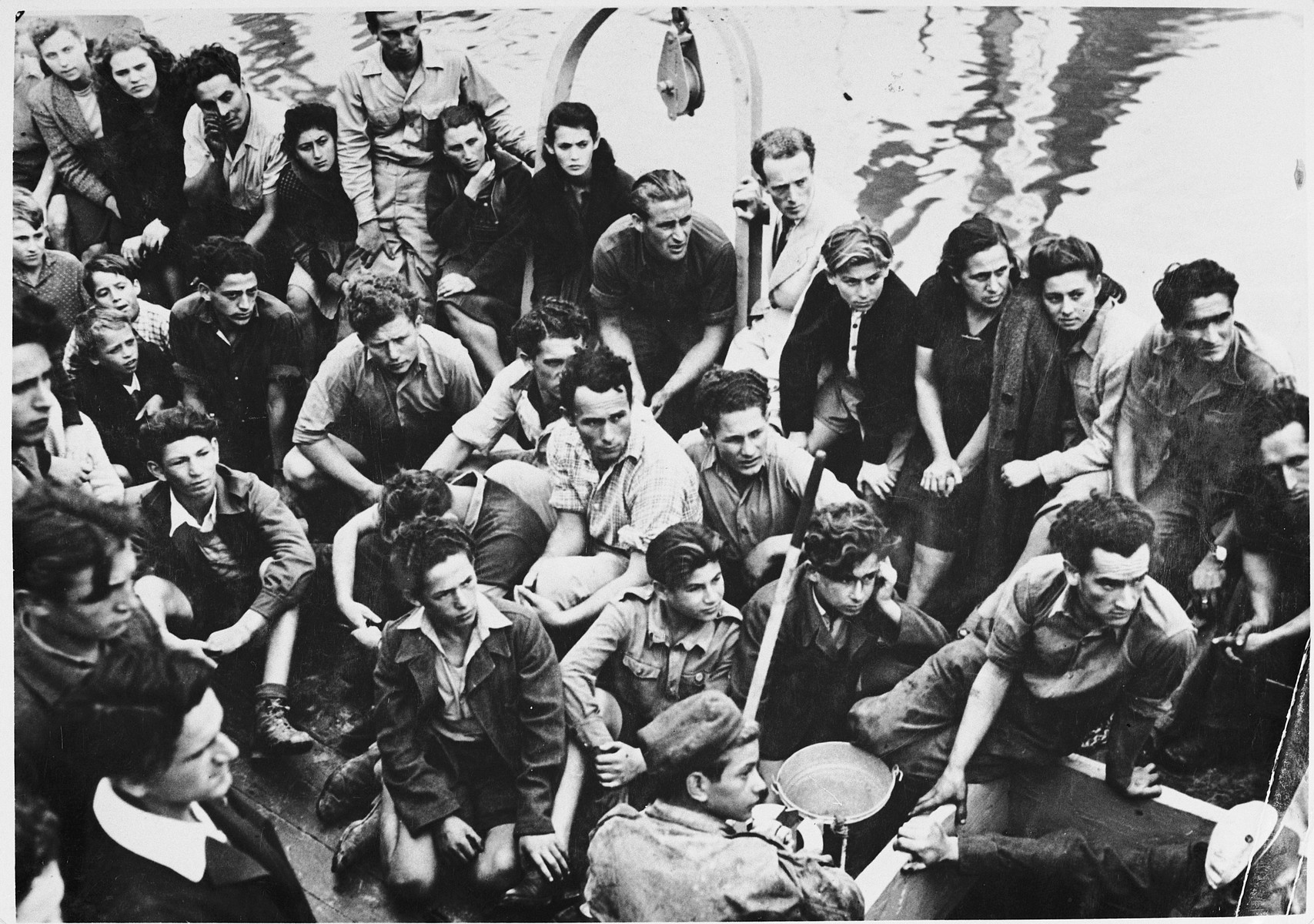 Jewish DPs who are members of the Migdalor hachshara, a maritime Zionist collective in Fano, Italy, crowd on the deck of a fishing boat.

Among those pictured are Kozik (bottom, left); middle row (right to left): Sevek, unknown, Zucker. and Vladek.  Top row (right to left): Daniel Sarchuk, Sigmund Zelig Braun, Eshter Nessel, her mother, unknown, Yaakov Neihof, Patt, Rusha, Zlatka, Karol, Roza, Yidl, Leah Rosenberg, and Chana Beler.