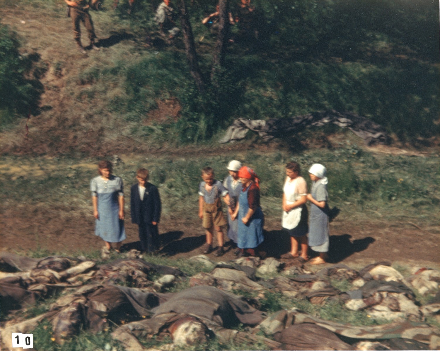 German civilians walk among the corpses of prisoners exhumed from a mass grave near the town of Nammering.